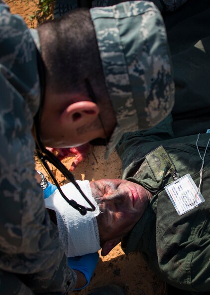Eglin’s 96th Medical Group Airman treat a victim's head wound during a major accident response exercise Aug. 6 at Duke Field.  Emergency responders from the base and the city were called to a downed aircraft scenario featuring fire, wreckage and victims with multiple injuries. The responders had to work as a team and coordinate movements at the simulated crash site, put out fires and attend to the wounded victims. (U.S. Air Force photo/Tech. Sgt. Jasmin Taylor)