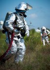 An Eglin Air Force Base firefighter stands by to engage the fire during a major accident response exercise Aug. 6 at Duke Field.  The simulated accident was a mid-air collision of a 33rd Fighter Wing joint strike fighter and a 919th Special Operations Wing C-145. Emergency responders from the base and the city were called to a downed aircraft scenario featuring fire, wreckage and victims with multiple injuries. The responders had to work as a team and coordinate movements at the simulated crash site, put out fires and attend to the wounded victims. (U.S. Air Force photo/Tech. Sgt. Jasmin Taylor)