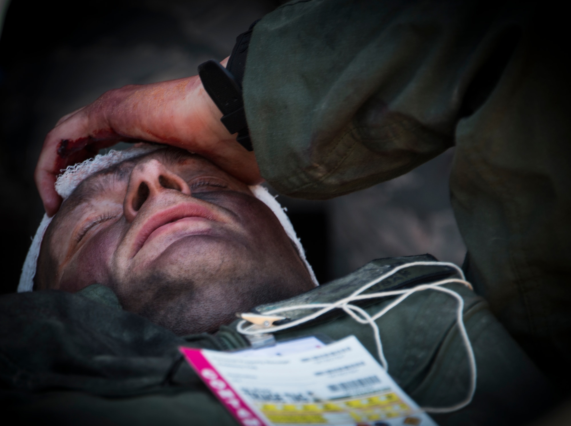 Master Sgt. Michael Sims, 5th Special Operations Squadron, simulates the pain from a head wound during a major accident response exercise Aug. 6 at Duke Field.  The simulated accident was a mid-air collision of a 33rd Fighter Wing joint strike fighter and a 919th Special Operations Wing C-145. Emergency responders from the base and the city were called to a downed aircraft scenario featuring fire, wreckage and victims with multiple injuries. The responders had to work as a team and coordinate movements at the simulated crash site, put out fires and attend to the wounded victims. (U.S. Air Force photo/Tech. Sgt. Jasmin Taylor)