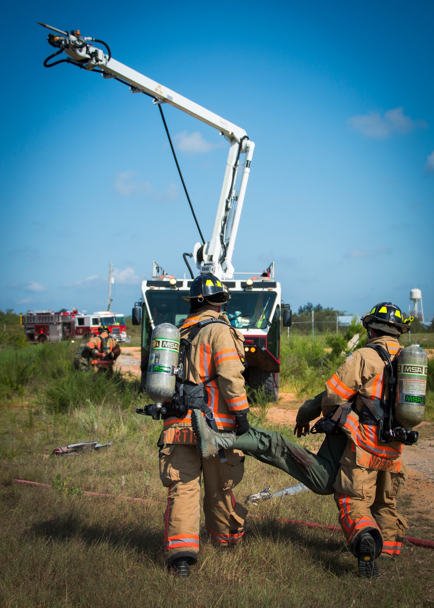 Eglin Air Force Base firefighters carry an injured victim to safety during a major accident response exercise Aug. 6 at Duke Field.  The simulated accident was a mid-air collision of a 33rd Fighter Wing joint strike fighter and a 919th Special Operations Wing C-145. Emergency responders from the base and the city were called to a downed aircraft scenario featuring fire, wreckage and victims with multiple injuries. The responders had to work as a team and coordinate movements at the simulated crash site, put out fires and attend to the wounded victims. (U.S. Air Force photo/Tech. Sgt. Jasmin Taylor)