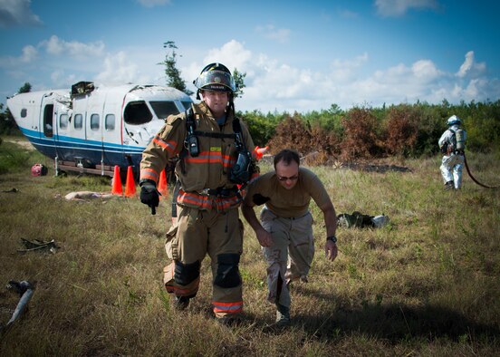 An Eglin Air Force Base firefighter carries a victim to the medical staging area during a major accident response exercise Aug. 6 at Duke Field.  The simulated accident was a mid-air collision of a 33rd Fighter Wing joint strike fighter and a 919th Special Operations Wing C-145. Emergency responders from the base and the city were called to a downed aircraft scenario featuring fire, wreckage and victims with multiple injuries. The responders had to work as a team and coordinate movements at the simulated crash site, put out fires and attend to the wounded victims. (U.S. Air Force photo/Tech. Sgt. Jasmin Taylor)