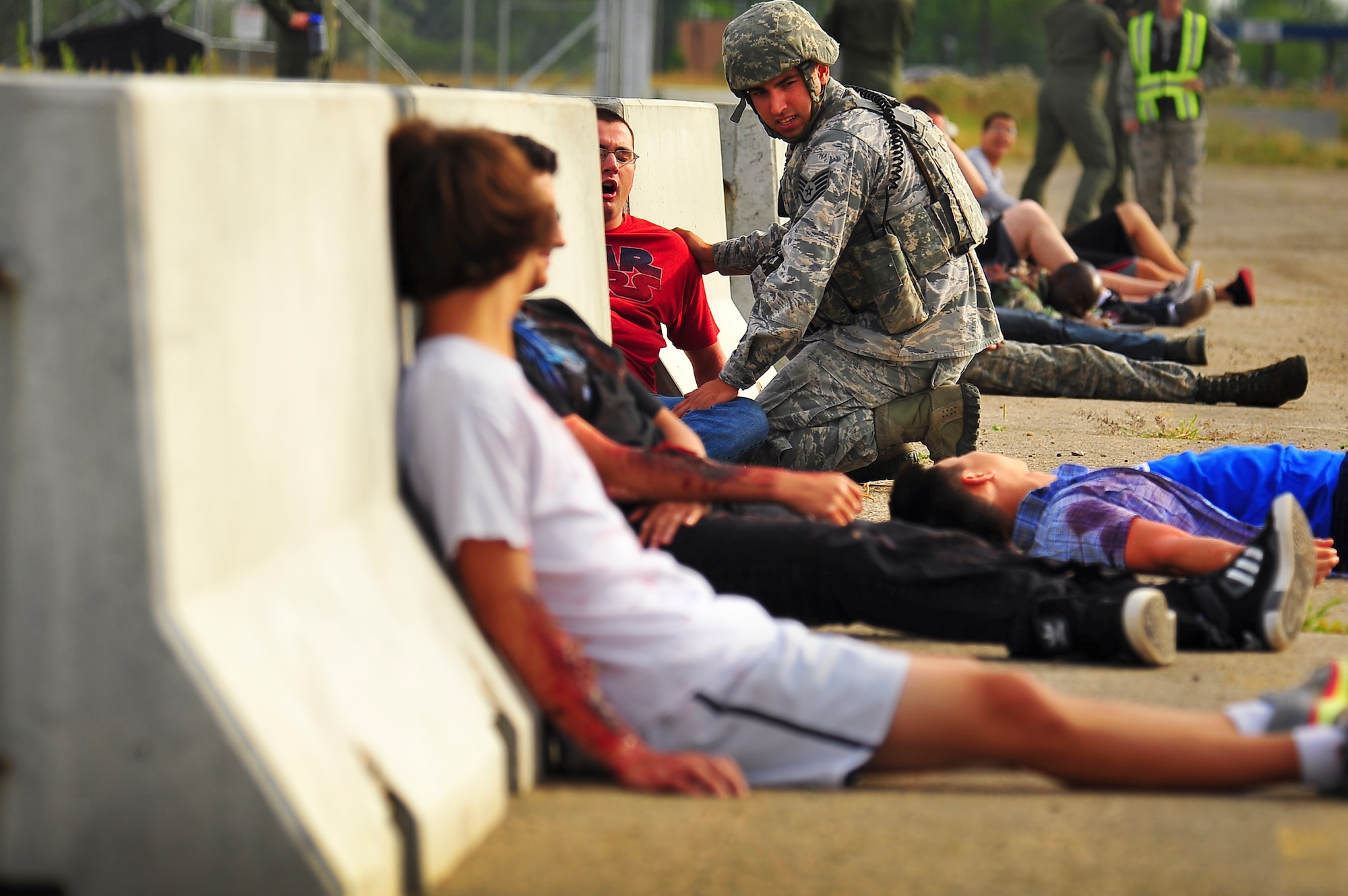 Staff Sgt. Sergio Hernandez, 5th Security Forces Squadron military working dog handler, tends to simulated wounded victims during an exercise on Minot Air Force Base, N.D., Aug. 5, 2014. The purpose of the exercise was to evaluate and validate the integration and response of emergency management, security forces, fire department, bioenvironmental and medical response members in a simulated radiological terrorist incident on Minot AFB. (U.S. Air Force photo/Senior Airman Brittany Y. Bateman)