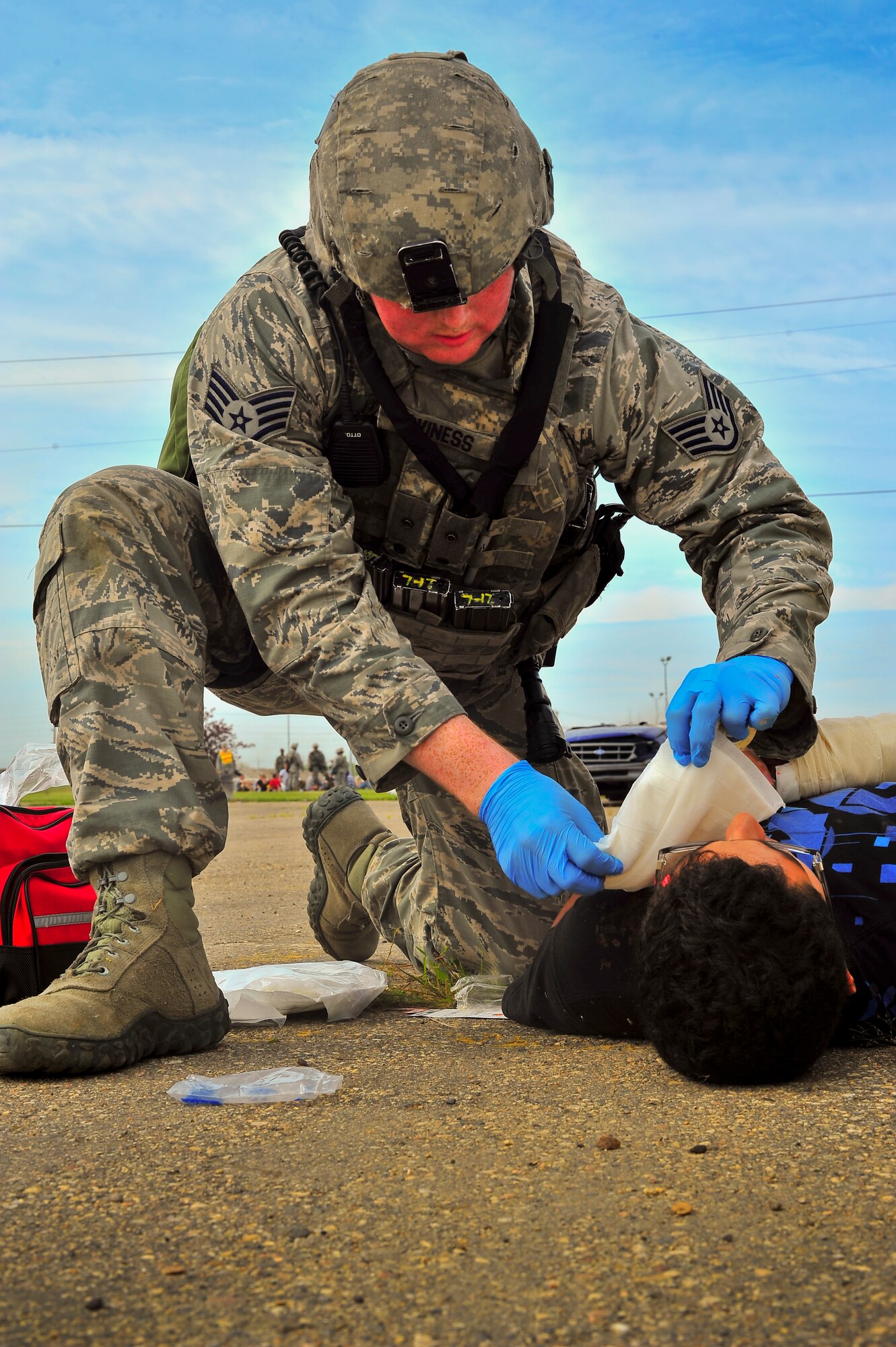 Staff Sgt. Shane Caviness, 5th Security Forces Squadron member, provides medical support to a simulated wounded victim during an exercise on Minot Air Force Base, N.D., Aug. 5, 2014. The purpose of the exercise was to evaluate and validate the integration and response of emergency management, security forces, fire department, bioenvironmental and medical response members in a simulated radiological terrorist incident on Minot AFB. (U.S. Air Force photo/Senior Airman Brittany Y. Bateman)