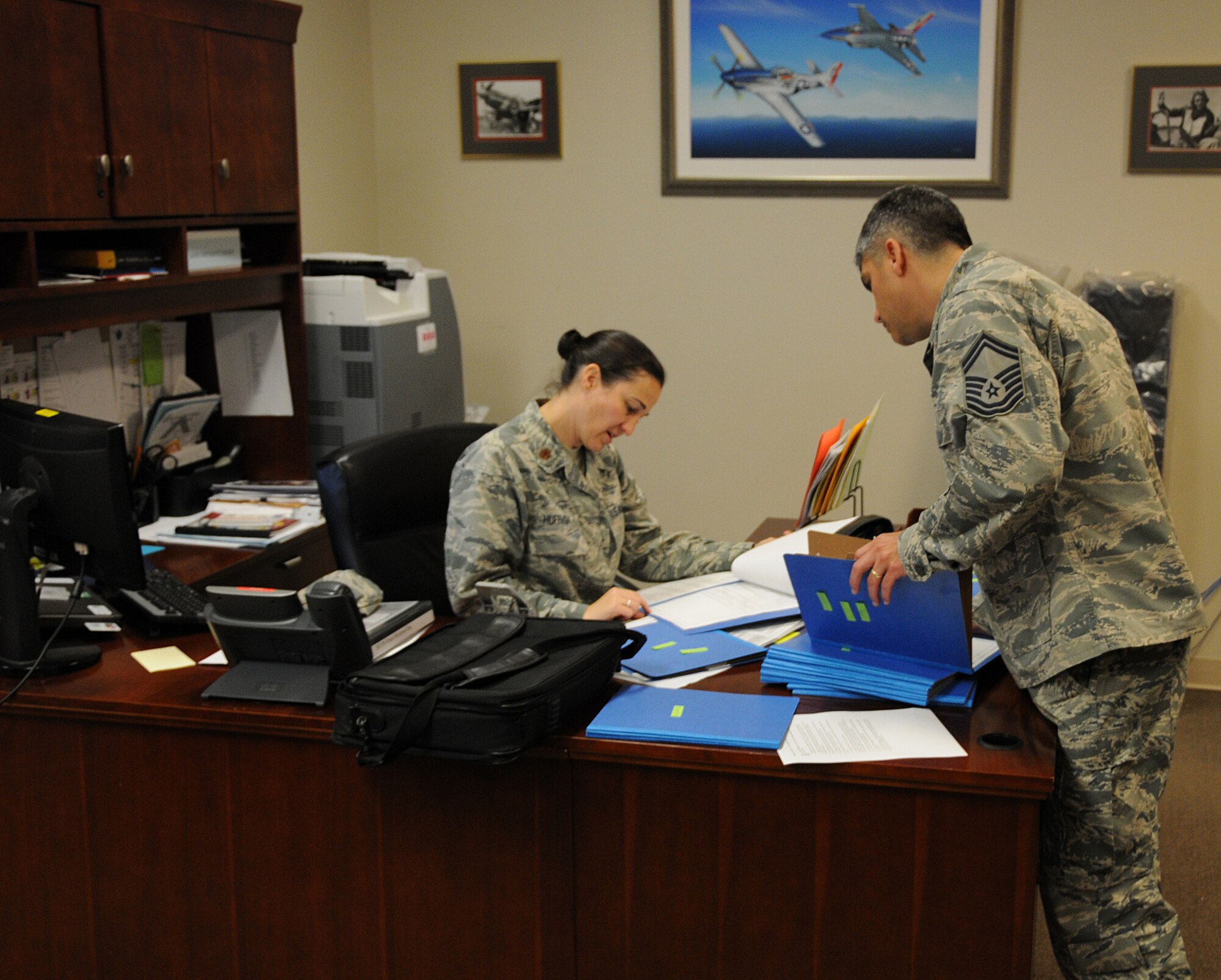 U.S. Air Force Major Emily Huffman (left), Commanders Executive Administrative Officer for the 192nd Fighter Wing collaborates with Senior Master Sgt. Jim Profita, 192nd Fighter Wing First Sergeant on building and updating physical readiness training records for wing members. Huffman manages the unit fitness program for the fighter wing staff. Additionally, she is the wing Sexual Assault Resource Coordinator for the fighter wing and manages all administrative responsibilities Profita was recently selected for promotion to Chief and will be transferring to the Mission Support Group where he will serve as the Group Chief. (U.S. Air National Guard photo by Capt. Craig Carper/Released)