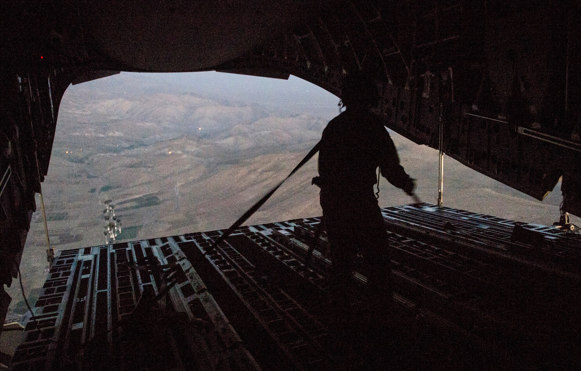 Tech. Sgt. Lynn Morelly, 816th Expeditionary Airlift Squadron, C-17 Globemaster III loadmaster, watches 28,224 halal meals parachute to the ground during a humanitarian airdrop mission over Iraq, Aug. 9, 2014. The humanitarian aid includes bottled water and food which was delivered to displaced citizens in the vicinity of Sinjar, Iraq. (U.S. Air Force photo by Staff Sgt. Vernon Young Jr.)