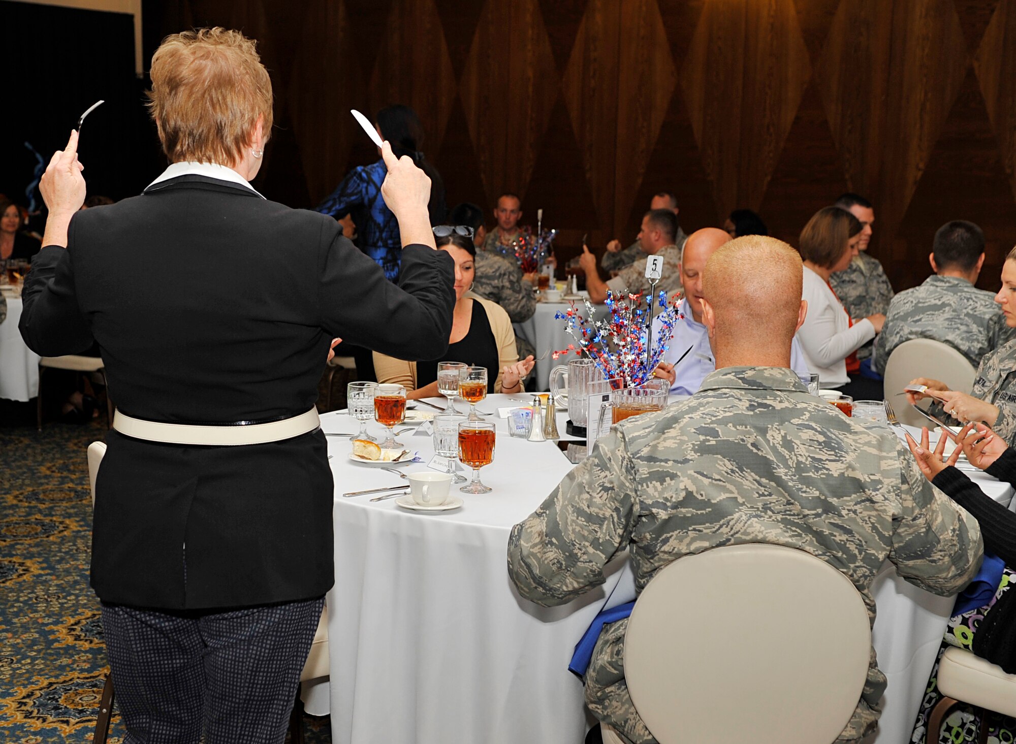 Fine-dining instructors walk around the room and demonstrate the proper way to hold a fork and knife during an etiquette course Aug. 1, 2014, at Ramstein Air Base, Germany. Protocol members learned the “do’s and don’ts” of protocol during the course. (U.S. Air Force photo/Airman Larissa Greatwood)