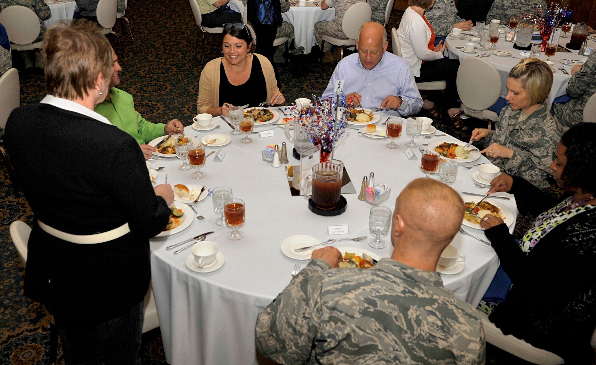 Fine-dining instructors walk around the room to answer questions from participants about dining etiquette during a portion of the Protocol Fundamental Course Aug. 1, 2014, at Ramstein Air Base, Germany. Protocol members learned the “do’s and don’ts” of protocol during the course. (U.S. Air Force photo/Airman Larissa Greatwood)