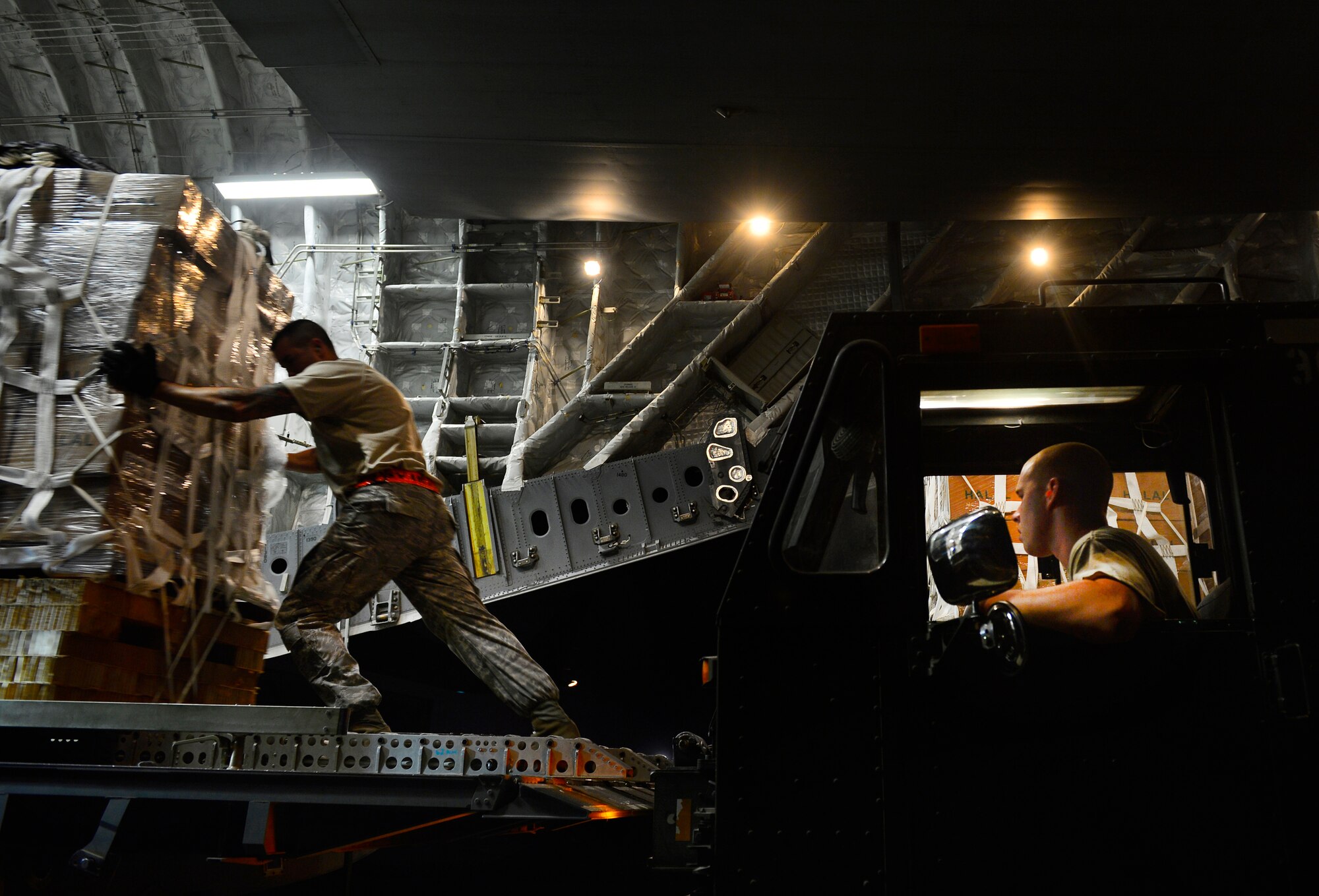 Staff Sgt. Daniel Leavindofske, 8th Expeditionary Air Mobility Squadron ramp team chief and Senior Airman David Babcock, air transportation journeyman, assist with loading 28,224 halal meals to a C-17 Globemaster III for a humanitarian airdrop mission over Iraq, Aug. 9, 2014, at a base in the U.S. Central Command area of responsibility. The humanitarian aid includes bottled water and food which was delivered to displaced citizens in the vicinity of Sinjar, Iraq. (U.S. Air Force photo by Staff Sgt. Vernon Young Jr.)