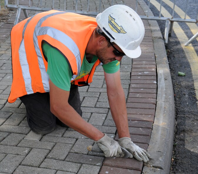 Matthew Bateson, a contractor from Kings Lynn, Norfolk, uses a trowel to place a gap between bricks Aug. 7, 2014, on RAF Mildenhall, England. The gap is essential to allow rain water to drain. (U.S. Air Force photo/Gina Randall/Released)