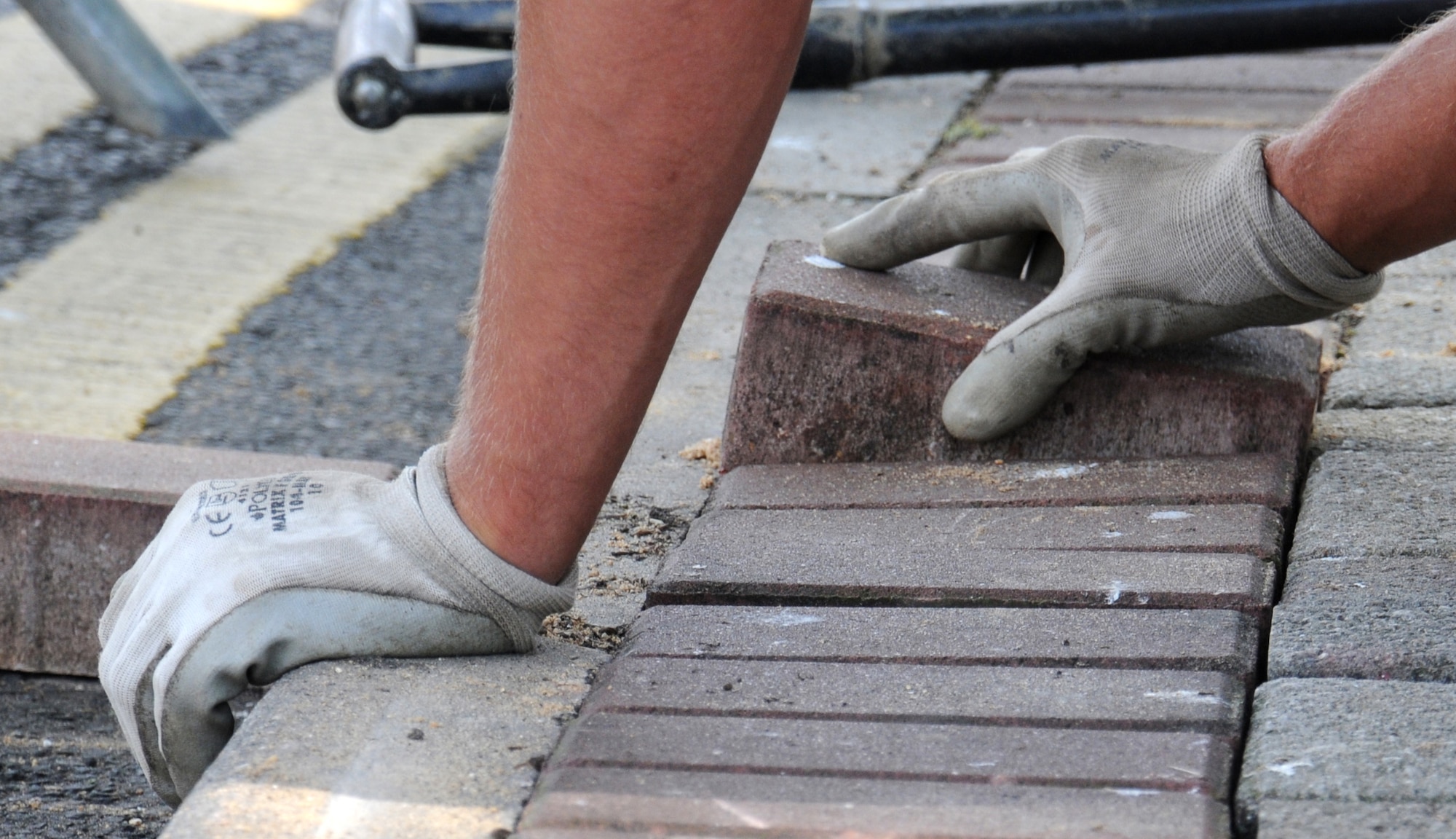 Matthew Bateson, a contractor from Kings Lynn, Norfolk, lays bricks on a bed of sand Aug. 7, 2014, on RAF Mildenhall, England. The sand is used when laying sidewalks to ensure the bricks are on a level surface. (U.S. Air Force photo/Gina Randall/Released)