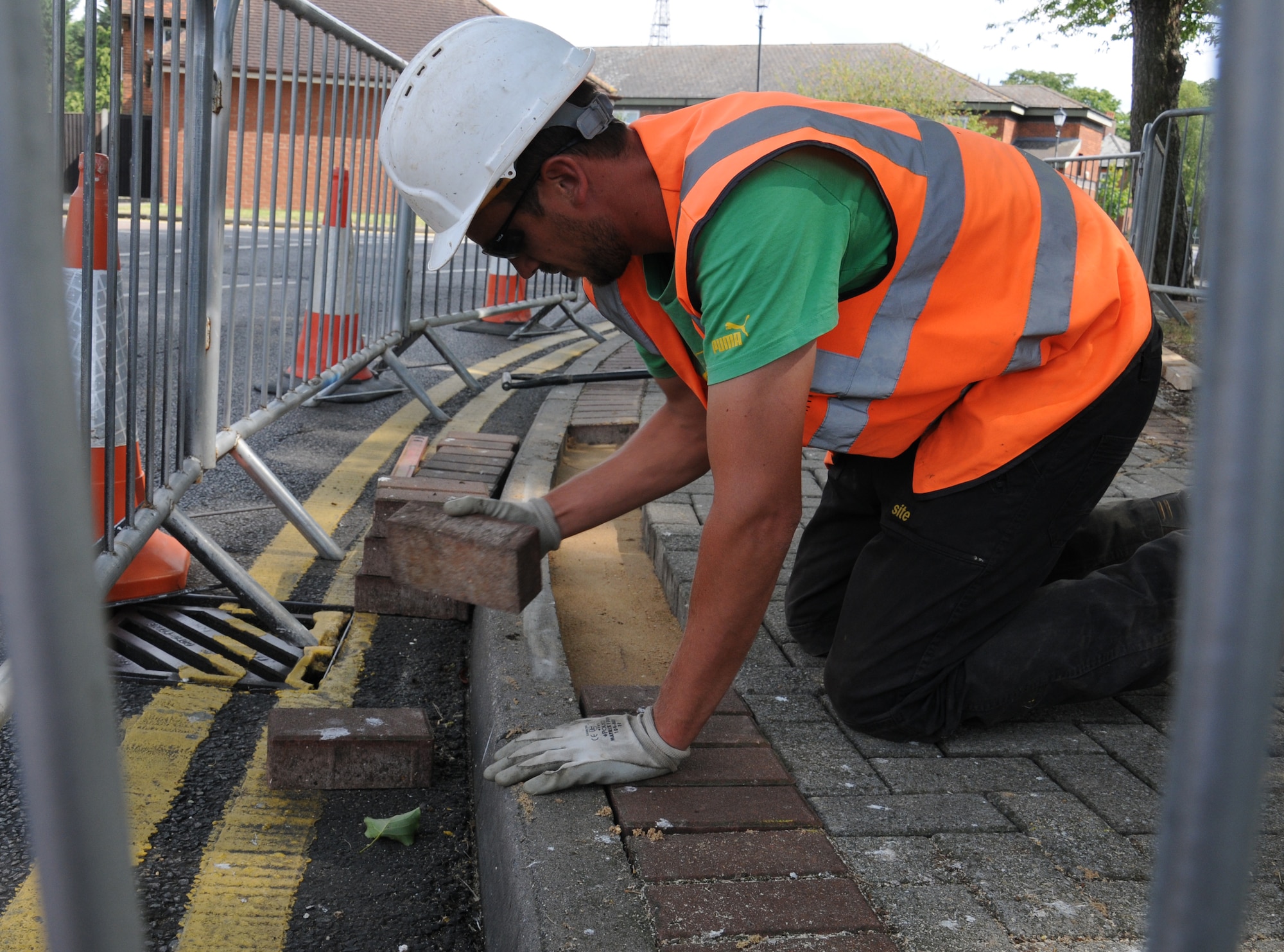 Matthew Bateson, a contractor from Kings Lynn, Norfolk, lays bricks on a bed of sand Aug. 7, 2014, on RAF Mildenhall, England. The sand is used when laying sidewalks to ensure the bricks are on a level surface. (U.S. Air Force photo/Gina Randall/Released)
