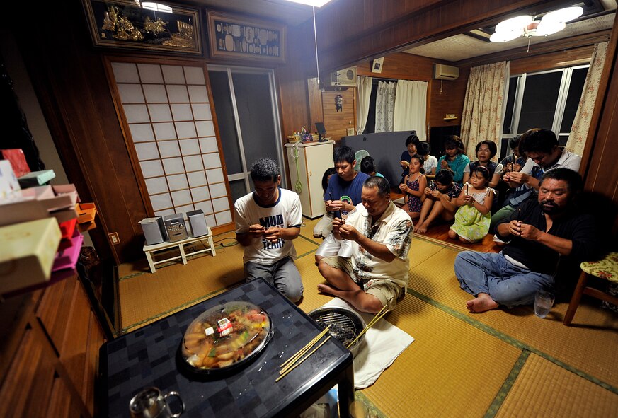 An Okinawan family gives thanks for their health and prays for their safety and happiness in front of Butsudan before sending ancestral spirits back to the other world at Yomitan village, Okinawa, Japan, Aug. 10, 2014. During Obon, which is one of the most important Japanese traditions, local people believe that the spirits of their departed ancestors come back to their homes to be reunited with their family. (U.S. Air Force photo by Naoto Anazawa)