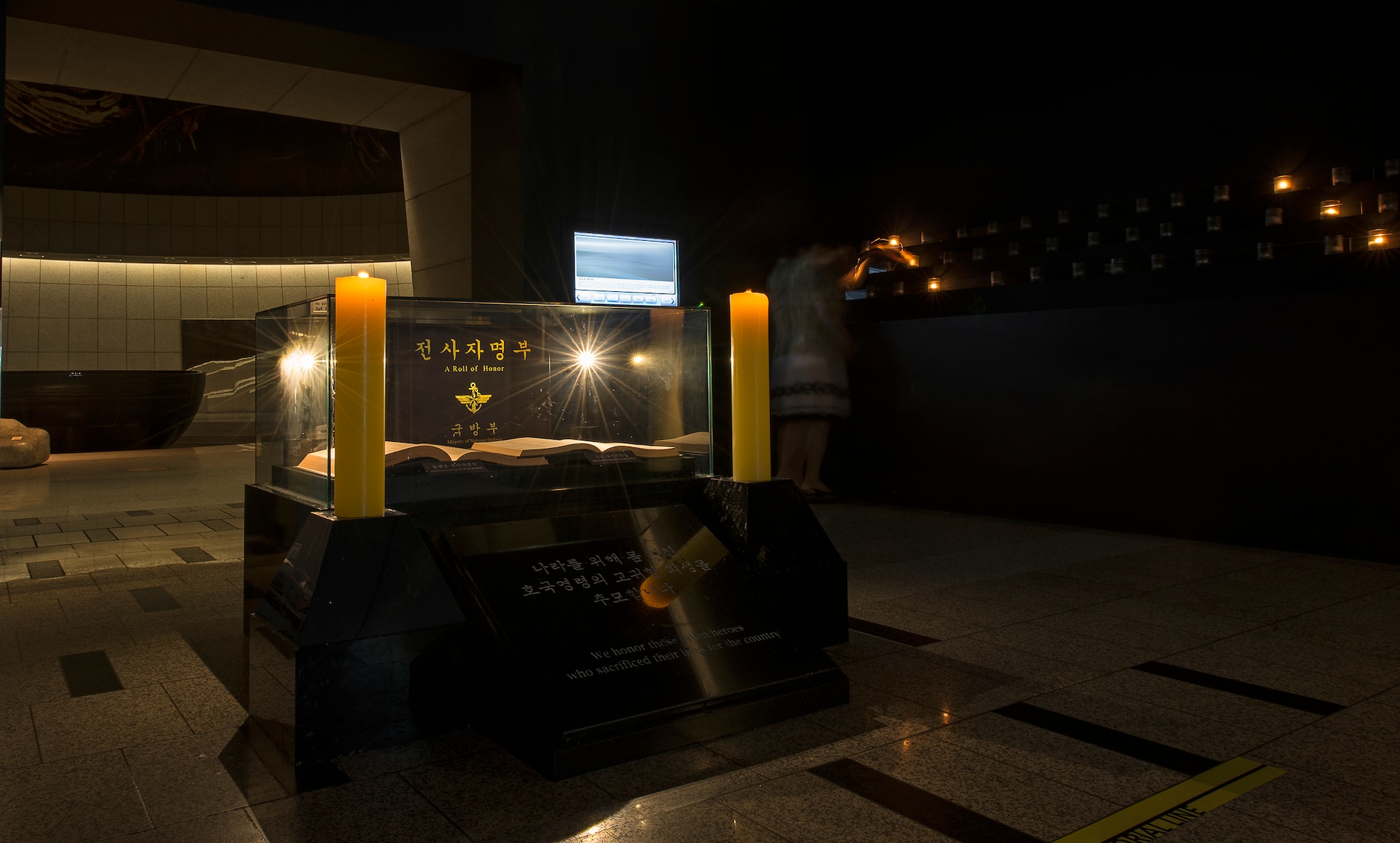 A museum employee lights a candle by the "Roll of Honor" at the War Memorial of Korea Aug. 2, 2014, in Seoul, Republic of Korea. The Roll of Honor, located in the Hall of Remembrance, is dedicated to the fallen who've died in service to the country of Korea. (U.S. Air Force photo by Staff Sgt. Jake Barreiro)