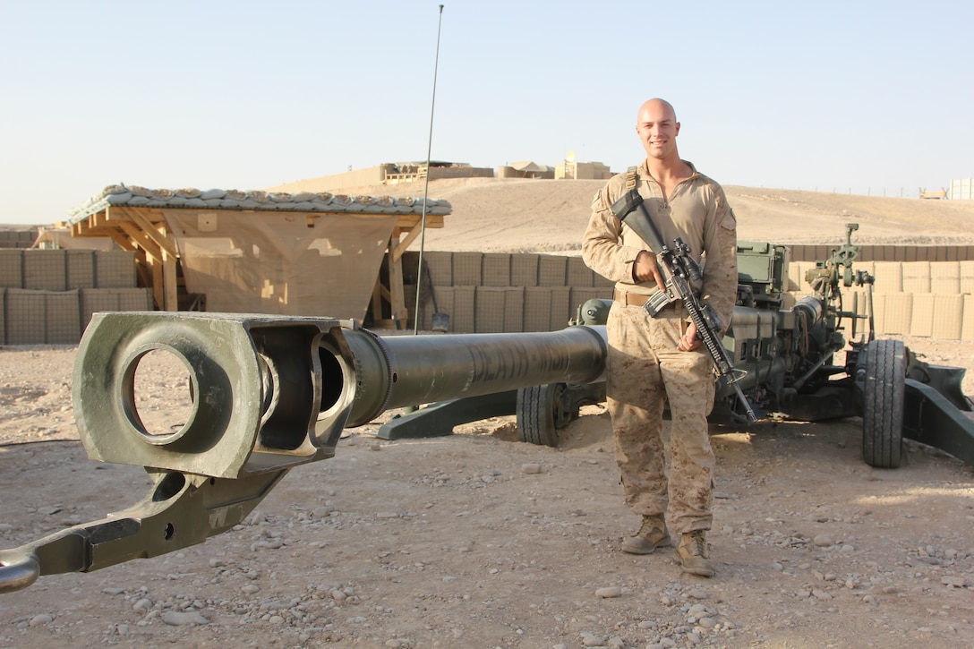 Corporal Shane Byram, a native of Sacramento, California and towed artillery system technician with Tango Battery, 5th Battalion, 11th Marine Regiment, poses for a photo next to a M777 howitzer aboard Camp Bastion, Helmand province, Afghanistan, July 21, 2014. Tango Battery has been vital to safeguarding the remaining U.S. and coalition forces in the region during 2014.