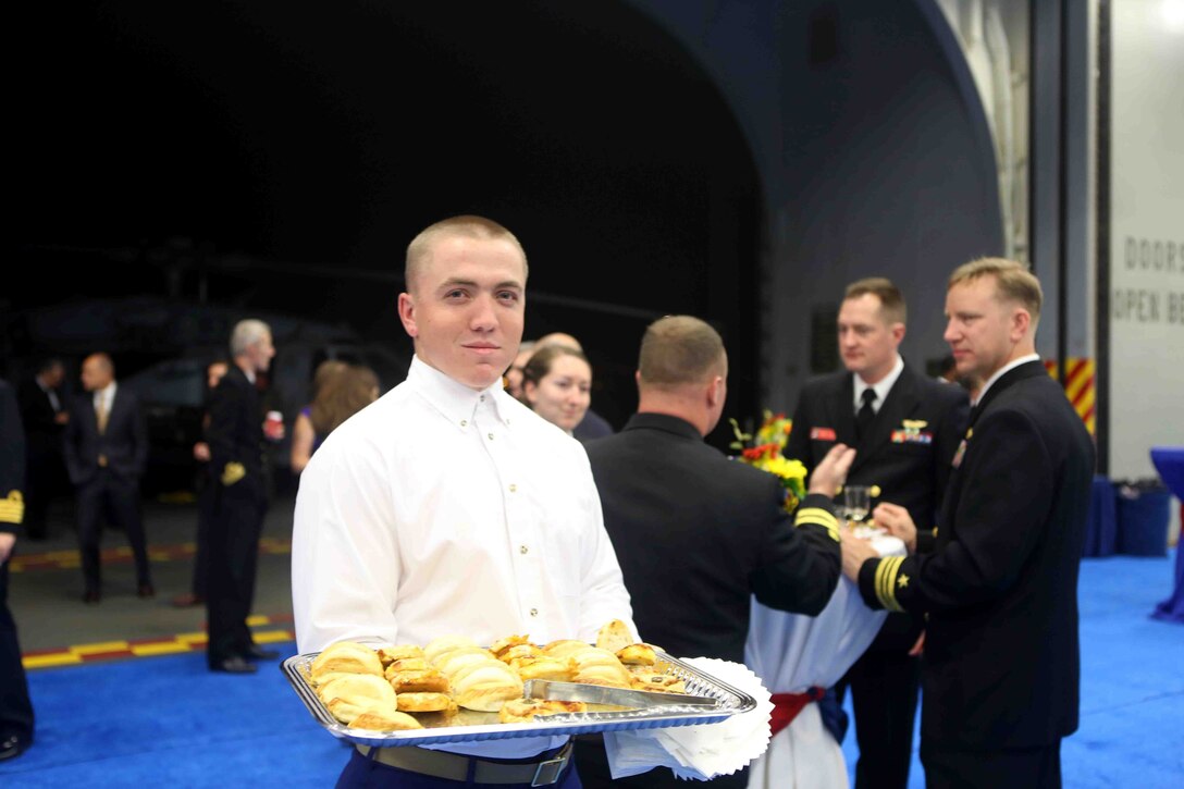 A Marine with Special Purpose Marine Air ground Task Force South presents a tray of food during a reception in the hanger bay of the future amphibious assault ship USS America (LHA 6) at Rio De Janeiro, Brazil, Aug. 7, 2014. The reception was hosted by the Sailors and Marines of America and SPMAGTF- South for Brazilian diplomats and military officials. The evening of food, music and dancing concluded with speeches from Rear Adm. Frank L. Ponds, commander of Expeditionary Strike Group 3 and The Honorable Liliana Ayalde, U.S. Ambassador to Brazil.  America is currently on her maiden transit, “America Visits the Americas”. The transit is a clear example of our Nation’s commitment to our regional partners and allies, demonstrating the Navy-Marine Corps integration in action. (U.S. Marine Corps photo by 1st Lt. Joshua Pena/Released)