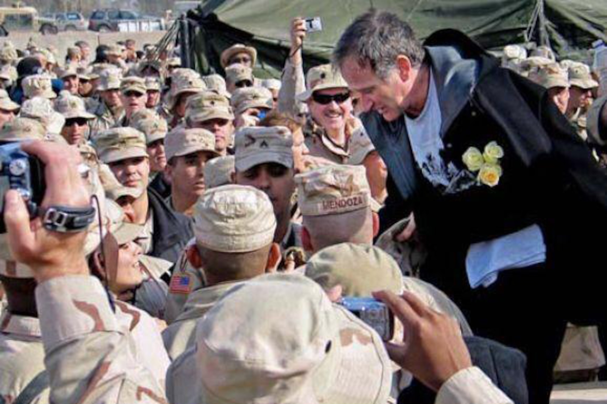 Robin Williams with troops gathered at the Camp Liberty Post Exchange in Baghdad during a USO tour, Dec. 14, 2004. DoD file photo by U.S. Army Sgt. Dan Purcell)   