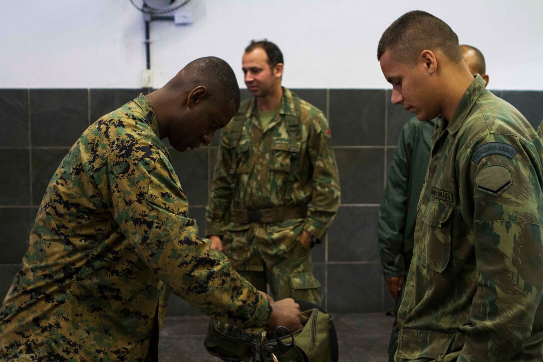 Petty Officer 1st Class Clarence Perry, U.S. Navy hospital corpsman with Special Purpose Marine Air Ground Task Force South, and a native of Franklin, Va., inspects a Brazilian field medical bag during a bi-lateral medical exchange at Marambaia Island, Brazil, Aug. 5, 2014. During the exchange, Brazilian Naval forces and U.S. Marines and Sailors shared medical tactics as part of a theater security cooperation event with the Logistics Combat Element of SPMAGTF-South. Through close cooperation, the U.S. and its partners are ready to address transnational security challenges through integrated and coordinated approaches. SPMAGTF-South is currently embarked aboard the future amphibious assault ship USS America (LHA 6) in support of her maiden transit, "America Visits the Americas." (U.S. Marine Corps Photo by Cpl. Donald Holbert/ Released)