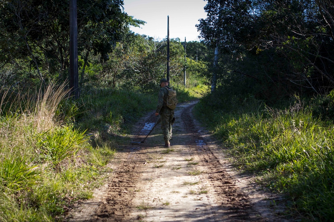 A Brazilian special forces Marine utilizes a mine detector to inspect a road for simulated improvised explosive devices during a counter IED course held on Marambaia Island, Brazil, Aug. 6, 2014. The counter IED course was conducted by U.S. and Brazilian Marines in conjunction with a combat tracking course as part of a theater security cooperation bi-lateral exchange. Through close cooperation, the U.S. and its partners are ready to address transnational security challenges through integrated and coordinated approaches. SPMAGTF-South is currently embarked aboard the future amphibious assault ship USS America (LHA 6) in support of her maiden transit, "America Visits the Americas." (U.S. Marine Corps Photo by Cpl. Donald Holbert/ Released)