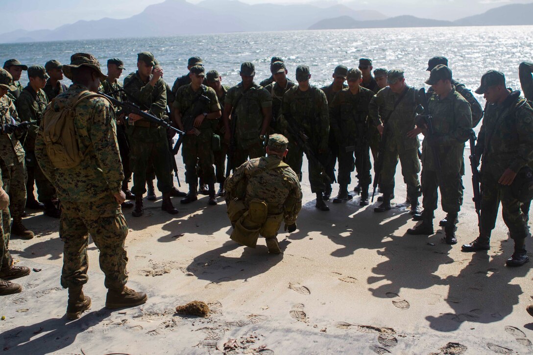 Brazilian Marines receive a mission brief from a Force Reconnaissance Marine with Special Purpose Marine Air Ground Task Force South during a combat tracking bi-lateral exchange conducted on Marambaia Island, Brazil Aug. 5, 2015. During the exchange, Brazilian and U.S. Marines shared their tactics on tracking enemy personnel and how to spot hidden improvised explosive devices. Through close cooperation, the U.S. and its partners are ready to address transnational security challenges through integrated and coordinated approaches. SPMAGTF-South is currently embarked aboard the future amphibious assault ship USS America (LHA 6) in support of her maiden transit, "America visits the Americas." (U.S. Marine Corps Photo by Cpl. Donald Holbert/ Released)