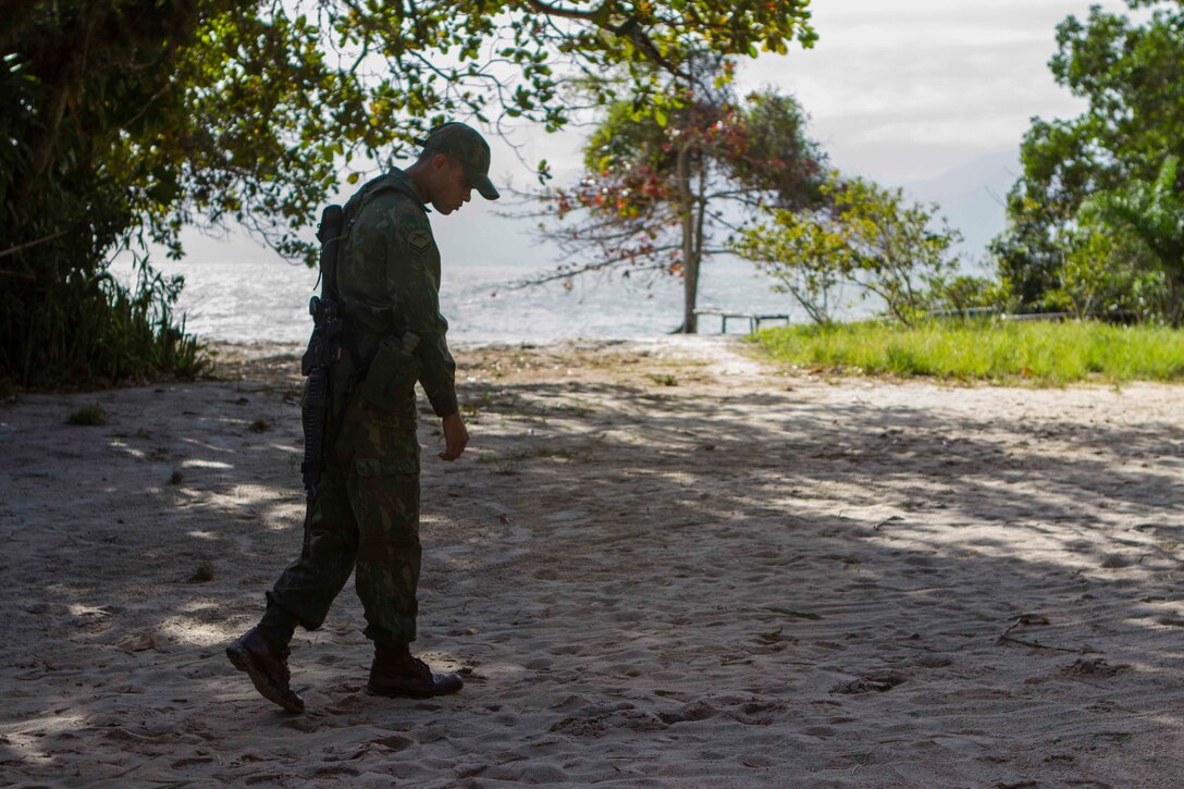 A Brazilian Marine analyzes markings made in the sand during a combat tracking bi-lateral exchange on Marambaia Island, Aug. 5, 2014. During the exchange, Brazilian and U.S. Marines with Special Purpose Marine Air Ground Task Force South shared their tactics on tracking enemy personnel and how to spot hidden improvised explosive devices. Through close cooperation, the U.S. and its partners are ready to address transnational security challenges through integrated and coordinated approaches. SPMAGTF-South is currently embarked aboard the future amphibious assault ship USS America (LHA 6) in support of her maiden transit, "America visits the Americas." (U.S. Marine Corps Photo by Cpl. Donald Holbert/ Released)