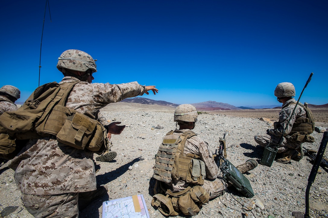 1st Lieutenant Davin Heaton, left, Fire Support Team leader and a weapons platoon commander for 1st Battalion, 1st Marine Regiment, 1st Marine Expeditionary Brigade, instructs his team on what targets to engage with artillery and air fire, while conducting combined arms training in support of Large Scale Exercise 2014 aboard Marine Corps Air Ground Combat Center Twentynine Palms, Calif., Aug. 9. LSE-14 is a bilateral training exercise being conducted by 1st MEB to build U.S. and Canadian forces’ joint capabilities through live, simulated, and constructive military training activities from Aug. 8-14, 2014. (U.S. Marine Corps Photo by Cpl. Rick Hurtado/Released)