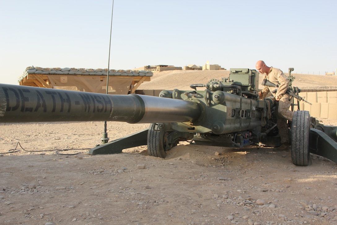 Cpl. Shane Byram, a native of Sacramento, California and towed artillery system technician with Tango Battery, 5th Battalion, 11th Marine Regiment, poses for a photo next to a M777 howitzer aboard Camp Bastion, Helmand province, Afghanistan, July 21, 2014. Tango Battery has been vital to safeguarding the remaining U.S. and coalition forces in the region during 2014.