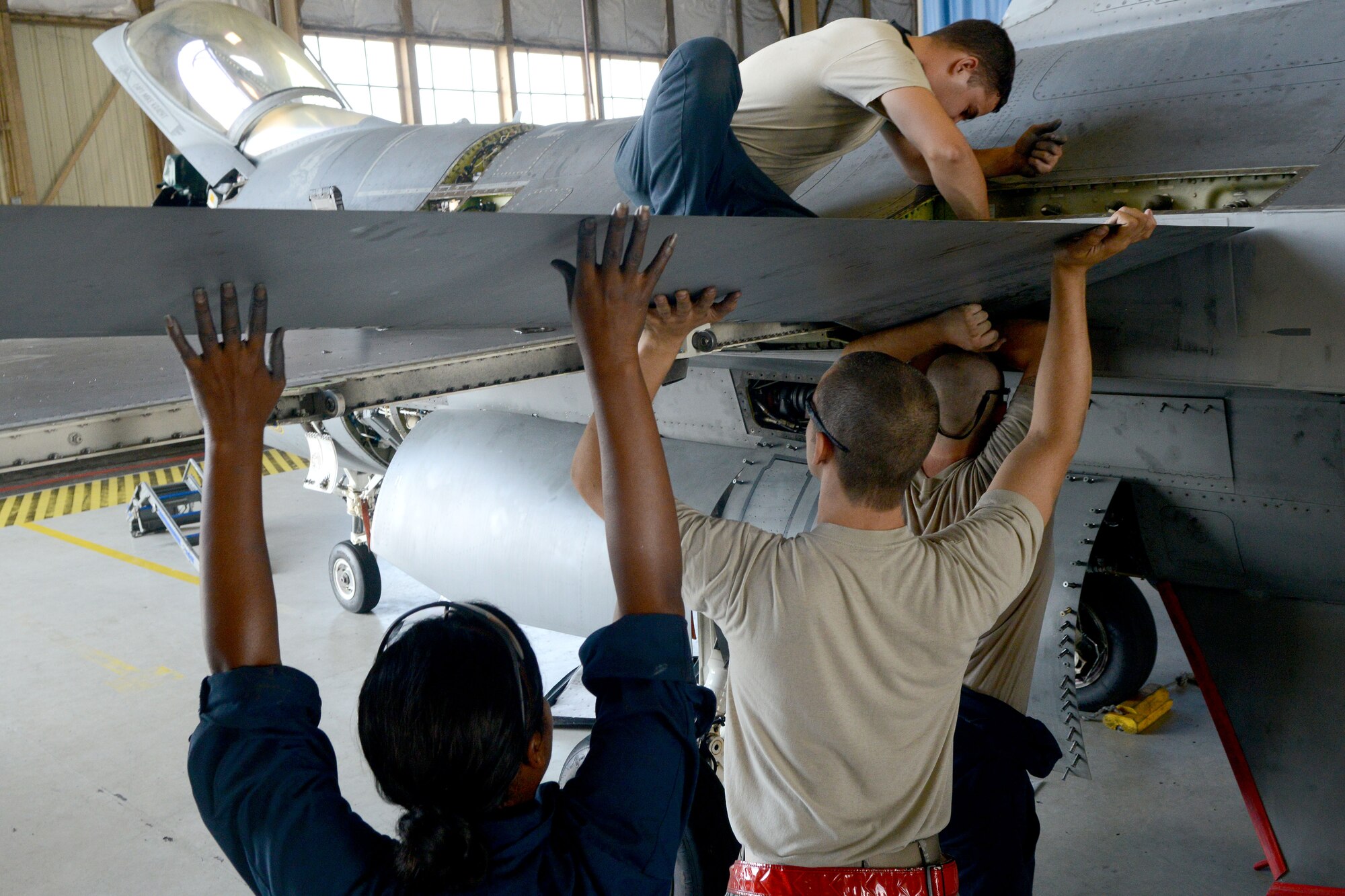 Airmen assigned to the 20th Equipment Maintenance Squadron attach an F-16CM Fighting Falcon wing to the body of the aircraft at Shaw Air Force Base, S.C., Aug. 6, 2014. The Airmen assigned to 20th EMS work around the clock to make sure aircraft are combat ready. (U.S. Air Force photo by Senior Airman Ashley Gardner/Released)