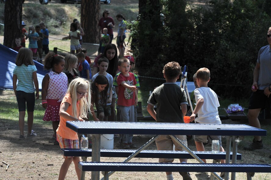 Children from the Fairchild Air Force Base Youth Center participate in a race on who can get the most water into a jar with a spoon at Clear Lake, Washington, Aug. 6, 2014. Children from age’s five to 12 were given the opportunity to work on several exercises to teach them how to procure water, fire safety, and navigation and camouflage. (U.S. Air Force photo by Staff Sgt. Alexandre Montes/Released)