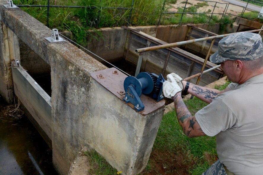 U.S. Air Force Tech. Sgt. Bryan Vaden, 20th Civil Engineer Squadron pavement and construction equipment operator, fixes a cable pulley attached to a storm drain at Shaw Air Force Base, S.C., Aug. 12, 2014. The storm drainis used to maintain water levels in the installation. (U.S. Air Force photo by Senior Airman Ashley L. Gardner/Released)