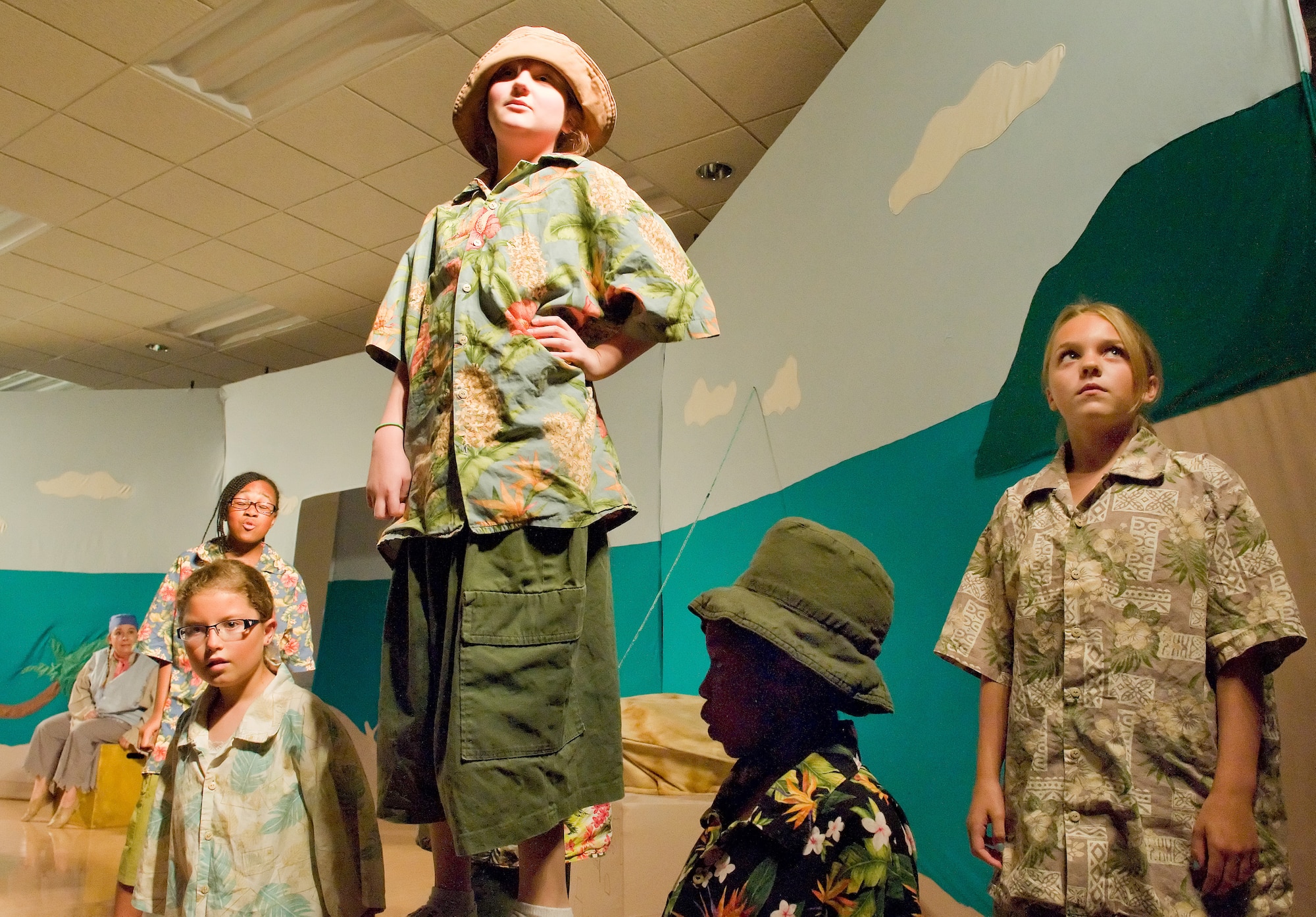 Children cast as beach bums in the musical "Blackbeard the Pirate" perform a scene as Jolly Rodger performed by Emilie LaBonte, tour actor/director from the Missoula Children's Theatre, Missoula, Montana, looks on from the background Aug. 8, 2014, at the Youth Center on Dover Air Force Base, Del. This was the ninth year the MCT has come to Dover AFB and was one of three military installations chosen to host the MCT during the summer tour of the play. (U.S. Air Force photo/Roland Balik)