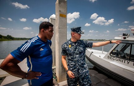 Petty Officer 2nd Class Brian Cobb, 628th Security Forces Squadron master at arms, briefs Herschel Walker, former NFL football player, on safety when entering and riding in a harbor patrol boat Aug. 6, 2014, at the Joint Base Charleston – Weapons Station, S.C. Cobb took Walker on a ride around the Harbor before Walker spoke with Sailors at the Bowman Center. Walker visited the base to share his story about growing up in Georgia, playing professional football and how he sought help from mental health professionals for his struggles with dissociative identity disorder. Walker spoke and met Sailors and Airmen at both the Weapons Station and Air Base where he met with service members and their families and signed autographs. Walker played college football at the University of Georgia and spent 14 years in the NFL. (U.S. Air Force photo / Senior Airman Tom Brading)