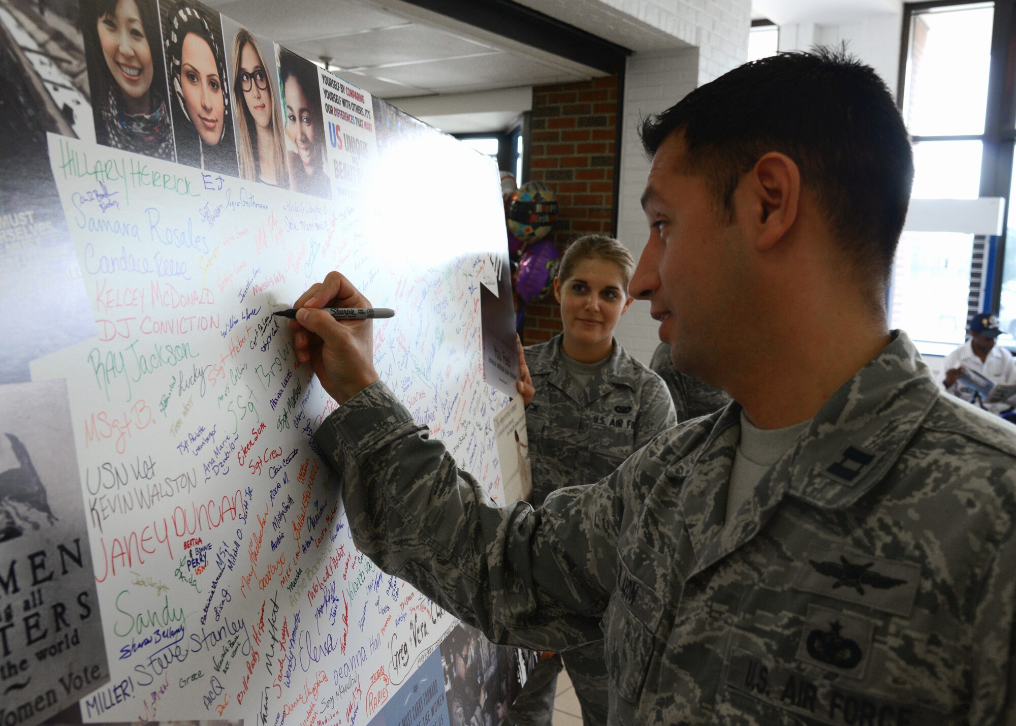 U.S. Air Force Capt. Jesus de Leon, 83rd Network Operations Squadron, signs the Joint Base Langley-Eustis Women’s Equality Wall in the Exchange atrium at Langley Air Force Base, Va., Aug. 12, 2014. Proceeds from donations, collected by the JBLE Women’s Equality Committee, will benefit area women’s and children’s shelters. Guests can donate and sign the wall daily from 11 a.m. to 1 p.m., through Aug. 19. (U.S. Air Force photo by Senior Airman Jason J. Brown/Released)