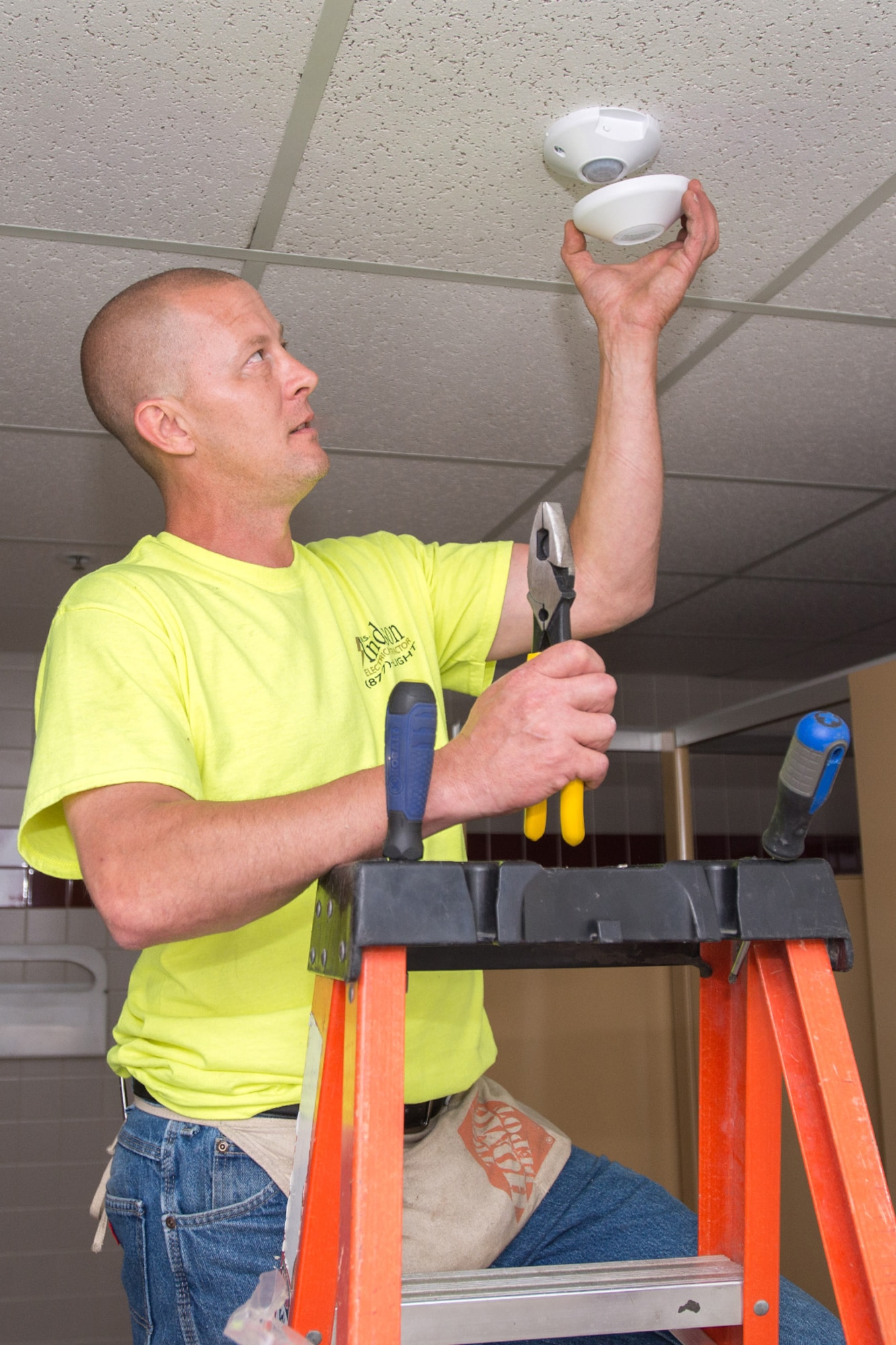 HANSCOM AIR FORCE BASE, Mass. – Paul Mann, W.S. Anderson technician, installs a lighting sensor in a restroom in Building 1624 Aug. 11 as part of several projects on base aimed to reduce the overall energy demand. Civil engineers assigned to the 66th Air Base Group through energy projects like this and others similar have saved the Air Force more than $70 million in savings to date. (U.S. Air Force photo by Rick Berry)