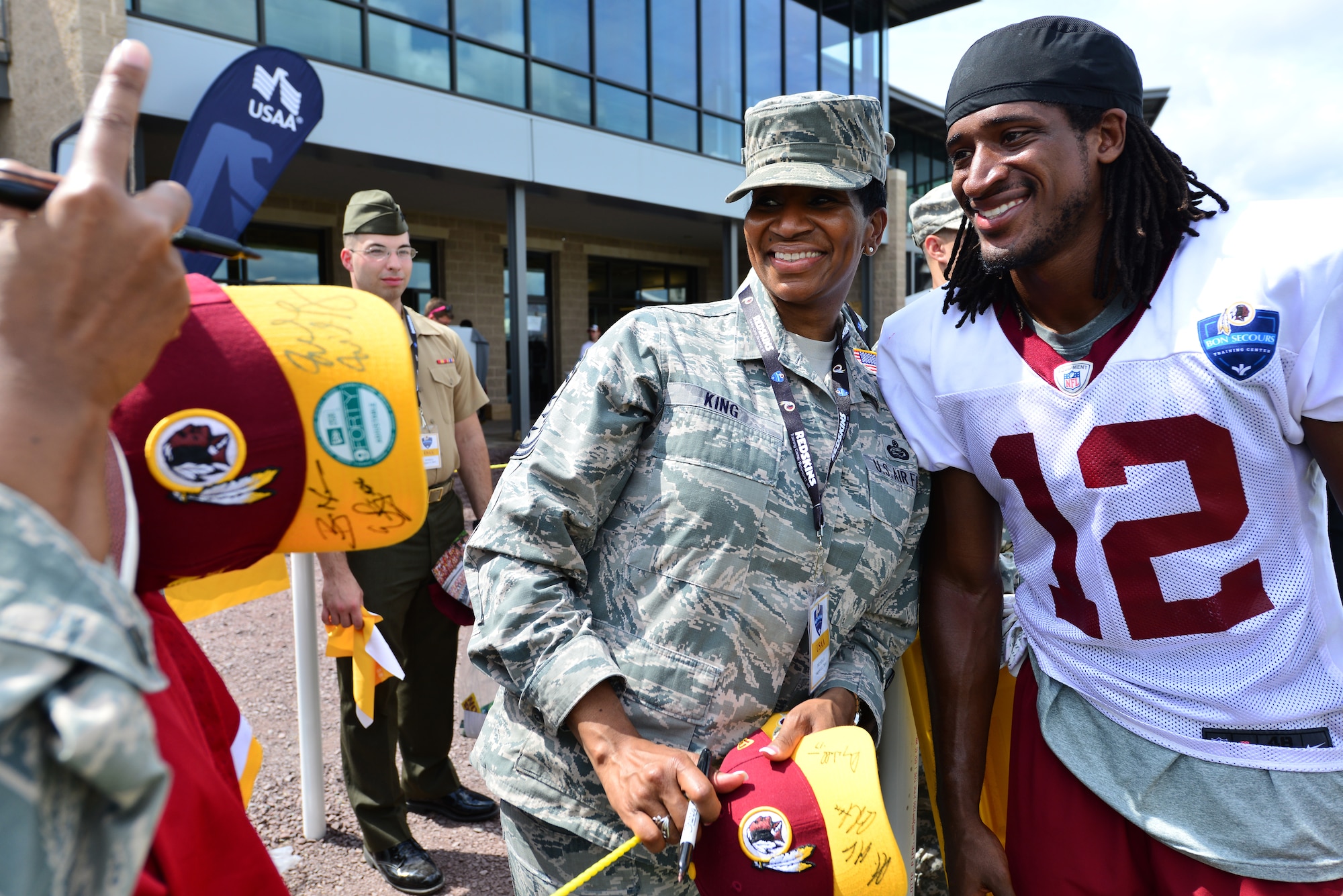 U.S. Air Force Chief Master Sgt. Trae King, 633rd Air Base Wing command chief, smiles for a photo with Andre Roberts, Washington Redskins wide receiver, after a training camp practice in Richmond, Va., Aug. 11, 2014. The event sponsored by USAA featured breakfast, goodie bags, a front-row seat to the practice and a meet-and-greet with team players. (U.S. Air Force photo by Senior Airman Aubrey White/released)
