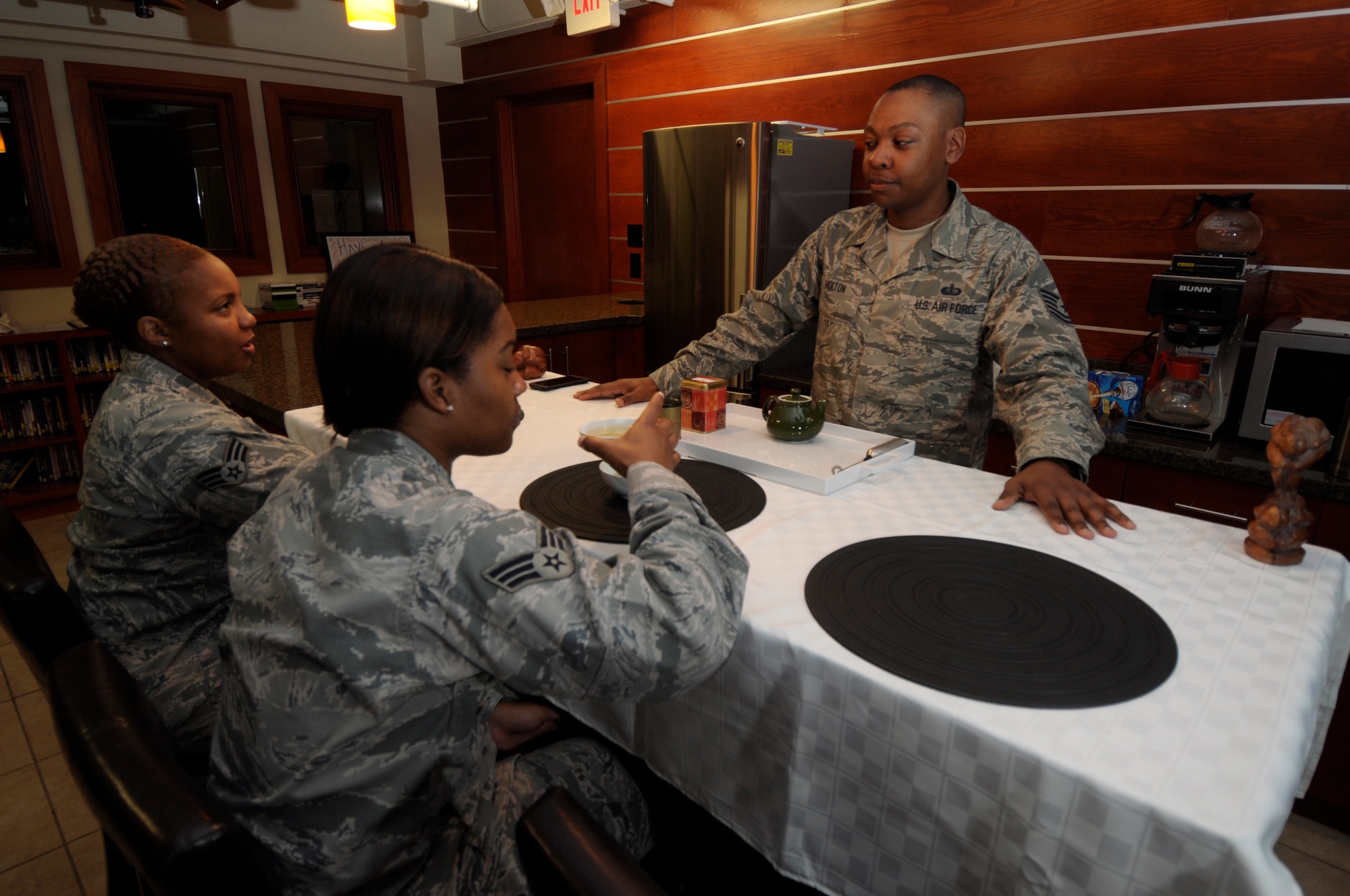 Tech. Sgt. Joseph Holton, 512th Memorial Affairs Squadron, watches as Senior Airmen Jaqe Wesley (left) and Tylisha Darling, 512th MAS, sample tea he made in the USO lounge of the Charles C. Carson Center for Mortuary Affairs, Dover Air Force Base, Del., Aug. 12, 2014. Holton shared tips on proper preparation and health benefits. Holton, Wesley and Darling are deployed to Air Force Mortuary Affairs Operations in support of the mortuary mission. (U.S. Air Force photo/Master Sgt. Christopher Gish)