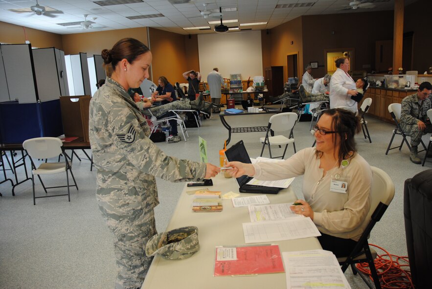 Monica Janssen, DAK-MINN Blood Bank donor resource coordinator, hands back Staff Sgt. Amanda Armenti her military common access card upon verifying her identity in order to make a blood donation on Aug. 6, 2014, at Sven's Den on Grand Forks Air Force Base, N.D. Armenti  was one of 12 members from  319th Medical Operations Squadron, who donated at the blood drive on base hosted by the 319th Medical Group.  (U.S. Air Force photo/Staff Sgt. Luis Loza Gutierrez)