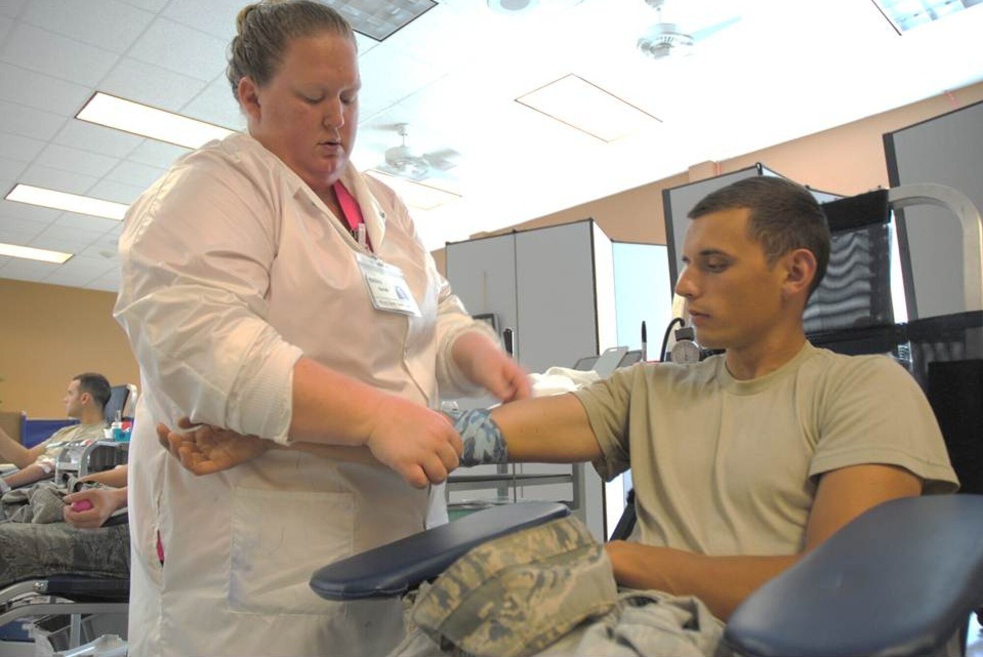 Sara Enlow, DAK-MINN Blood Bank technician uses a roll of blue camouflage to bandage Senior Airman Jacob Nevills, arm after a blood donation made by the 319th Civil Engineering Squadron Airmen on Aug. 6, 2014, at Sven's Den on Grand Forks Air Force Base, N.D. The 319th Medical Group partnered with DAK-MINN Blood Bank to help local hospital patients in need by hosting a blood drive on base. (U.S. Air Force photo/Staff Sgt. Luis Loza Gutierrez)