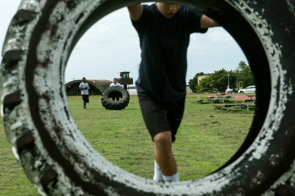 Students from Bitburg High School perform tire rolls during a Bitburg High School summer strength training session Aug. 6, 2014, at Spangdahlem Air Base, Germany. The students work out three days a week to stay in shape for the upcoming sports seasons. (U.S. Air Force photo by Senior Airman Rusty Frank/Released)