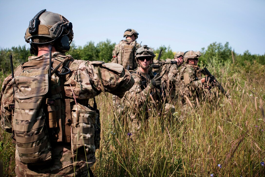 Air Force 2nd Lt. Paul Hauter, center, uses hand signals to communicate with Air Force Capt. Daniel Curtin, foreground, during Operation Northern Strike near Rogers City, Mich., Aug. 7, 2014. Hunter and Curtin are tactical air controllers assigned to the Illinois Air National Guard's 169th Air Support Operations Squadron.  
