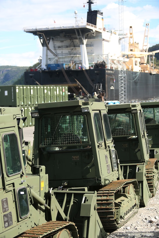 Military bulldozers and other equipment are staged for transportation at the designated offload pier during a pre-planned Single Ship Movement and offload of military equipment from a Maritime Prepositioning Force ship in the Trøndelag region of Norway.

U.S. Marines from 2nd Marine Logistics Group out of Camp Lejeune, NC, in coordination with their Norwegian counterparts, are modernizing some of the equipment currently stored within six caves as a part of the Marine Corps Prepositioning Program-Norway by placing approximately 350 containers of gear and nearly 400 pieces of heavy rolling stock into the storage caves.  

  Specific equipment which will greatly increase the program’s readiness includes M1A1 Main Battle Tanks, Tank Retrievers, Armored Breeching Vehicles, Amphibious Assault Vehicles, Expanded Capacity Vehicle (ECV) Gun Trucks and several variants of the MTVR 7 ½ ton trucks.  

Planning for this equipment refresh began in the spring of 2010.