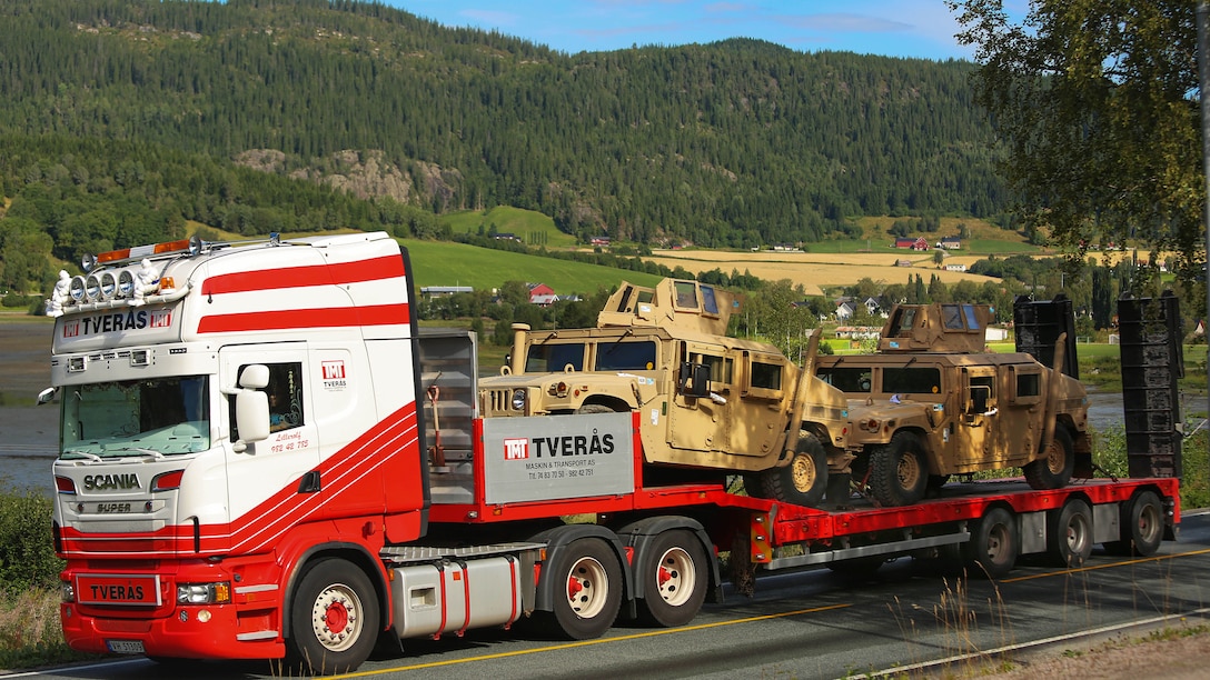 Armored variants of the M1114 High Mobility Multipurpose Wheeled Vehicle (HMMWV) are transported by truck from a ship offload location to one of six caves which make up the Marine Corps Prepositioning Program-Norway during an equipment modernization operation. U.S. Marines from 2nd Marine Logistics Group out of Camp Lejeune, NC, in coordination with their Norwegian counterparts, are modernizing some of the equipment by placing approximately 350 containers of gear and nearly 400 pieces of heavy rolling stock into the storage caves.  