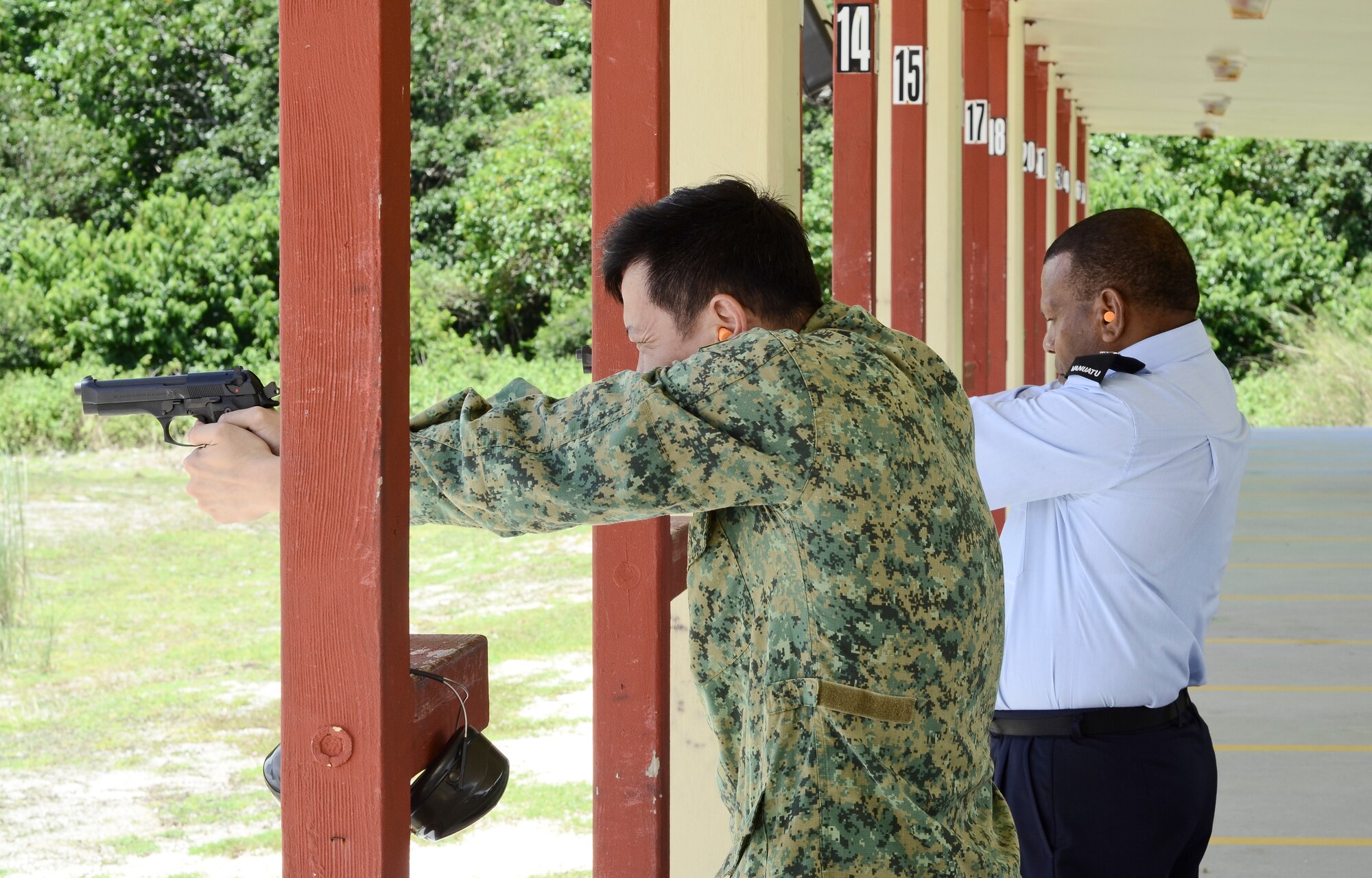 Participants in the Pacific Defender subject-matter expert exchange fire the 9 mm pistol Aug. 7, 2014, on Andersen Air Force Base, Guam.  During the exchange, military and police representatives from Singapore, Vanuatu, Bangladesh and the Maldives    toured 36th Contingency Response Group facilities and the 736th Security Forces Squadron. (U.S. Air Force photo by Staff Sgt. Robert Hicks/Released