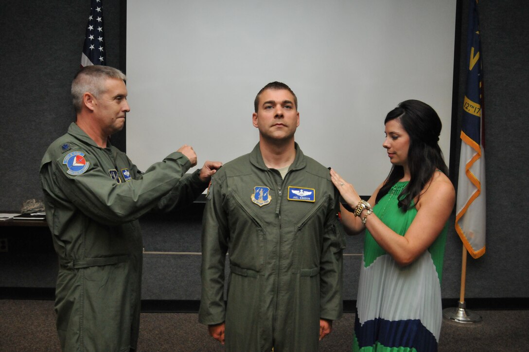 U.S. Air Force Capt. Joel Kingdon, a C-130H Hercules aircraft pilot for the 156th Airlift Squadron, is ceremoniously pinned to the rank of Major by his wife Jenna and Lt. Col. Bradley Holbrooks, pilot for the 156th AS, during a promotion ceremony held at the North Carolina Air National Guard base, Charlotte Douglas Intl. airport, August 2, 2014.
So far in his career, Kingdon has logged approximately 3,000 flight hours. (U.S. Air National Guard photo by Tech. Sgt. Rich Kerner, 145th Public Affairs/Released)