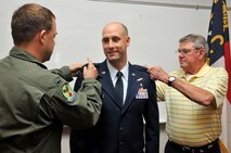 U.S. Air Force Maj. Lee W. Thompson, 145th Logistics Readiness Squadron commander, is ceremoniously pinned to the rank of Lieutenant Colonel by his father, Master Sgt. Leon Thompson, (ret.) and his brother 1st Lieutenant Lane Thompson, a flight nurse with the 156th Aeromedical Evacuation Squadron, during his promotion ceremony held at the North Carolina Air National Guard base, Charlotte Douglas Intl. airport, August 2, 2014. (U.S. Air National Guard photo by Senior Airman Laura Montgomery, 145th Public Affairs/Released)