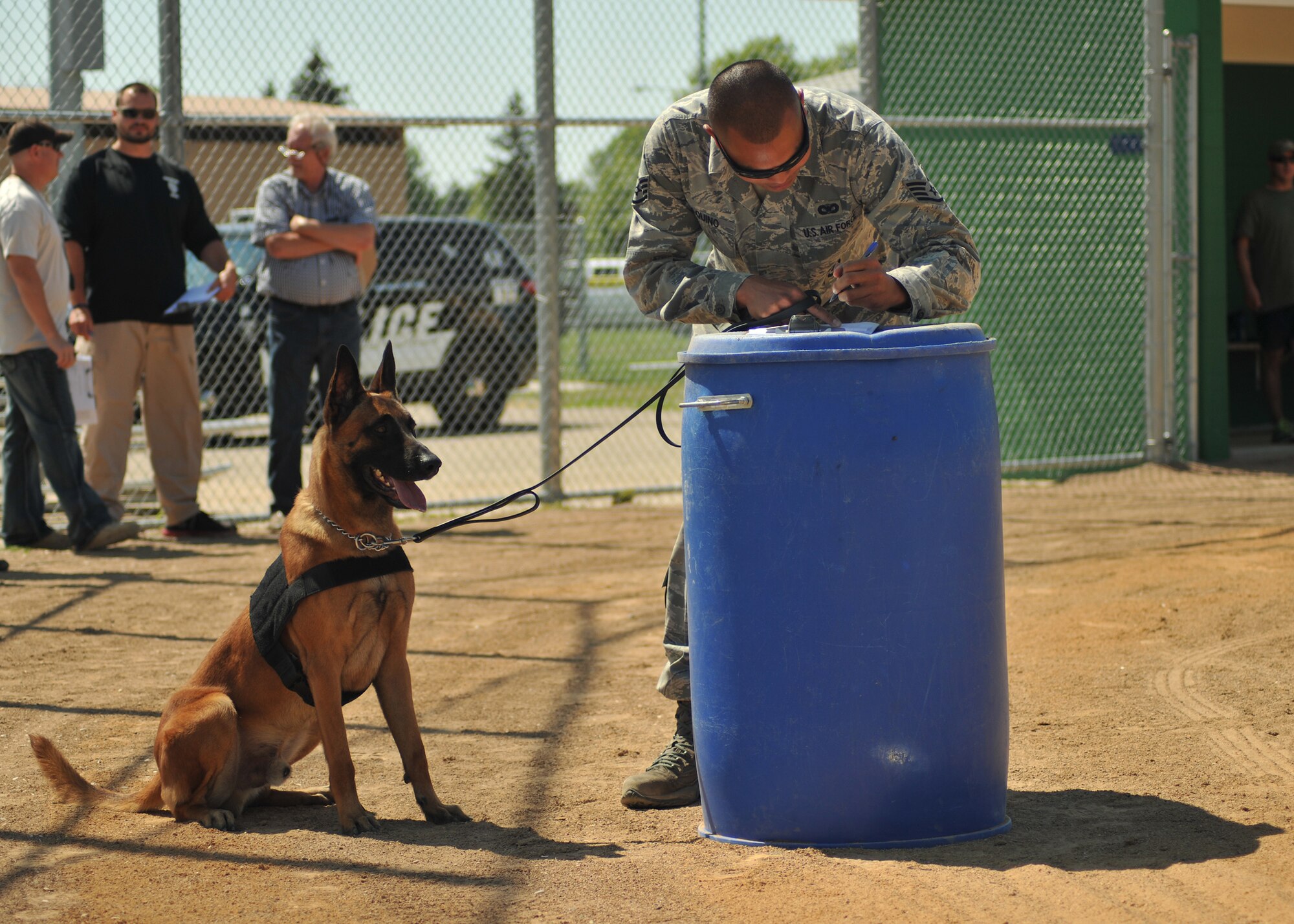 Military Working Dog, Llauren, sits still as her handler, Staff Sgt. Jesse Aquino, from the 319th Security Forces Squadron, fills out a K-9 questionnaire during the Iron Dog Course at Apollo Park on Aug. 13, 2014,  in the city of Grand Forks, N.D. The Iron Dog Course was one of three smaller competitions featured as part of the North Dakota Peace Officers Association’s K9 Challenge. (U.S. Air Force photo/Senior Airman Xavier Navarro)