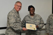 U.S. Air Force Col. Marshall C. Collins, 145th Airlift Wing commander, presents Capt. Trendce Hudson, a chaplain for the1 45th AW, with the Valuable Volunteer Award at the North Carolina Air National Guard Base, Charlotte Douglas Intl. airport, August 2, 2014. Hudson, along with over thirty NCANG members assisted with setting up food service and mentorship at the annual Special Olympics held at Lowes Motor Speedway, Charlotte, NC. (Air National Guard photo by Senior Airman Laura Montgomery, 145th Public Affairs/Released)

