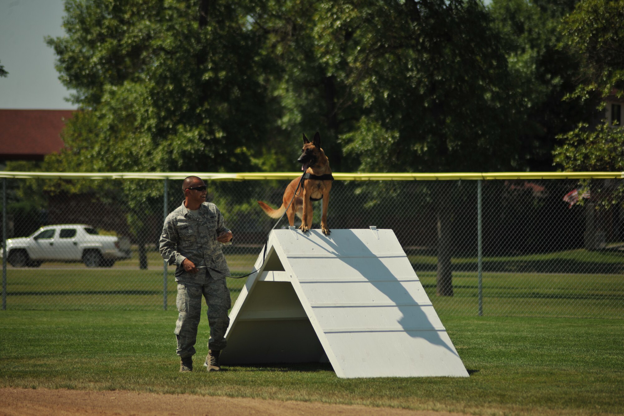 Staff Sgt. Jesse Aquino, 319th Security Forces Squadron military working dog handler, plays to the crows as he positions his K9 partner, Llauren, on top of an A-frame obstacle as the crowd applauds during the Iron Dog Course at Apollo Park on Aug. 13, 2014, in the city of Grand Forks, N.D. The Iron Dog Course was one of three smaller competitions featured as part of the North Dakota Peace Officers Association’s K9 Challenge. (U.S. Air Force photo/Senior Airman Xavier Navarro)