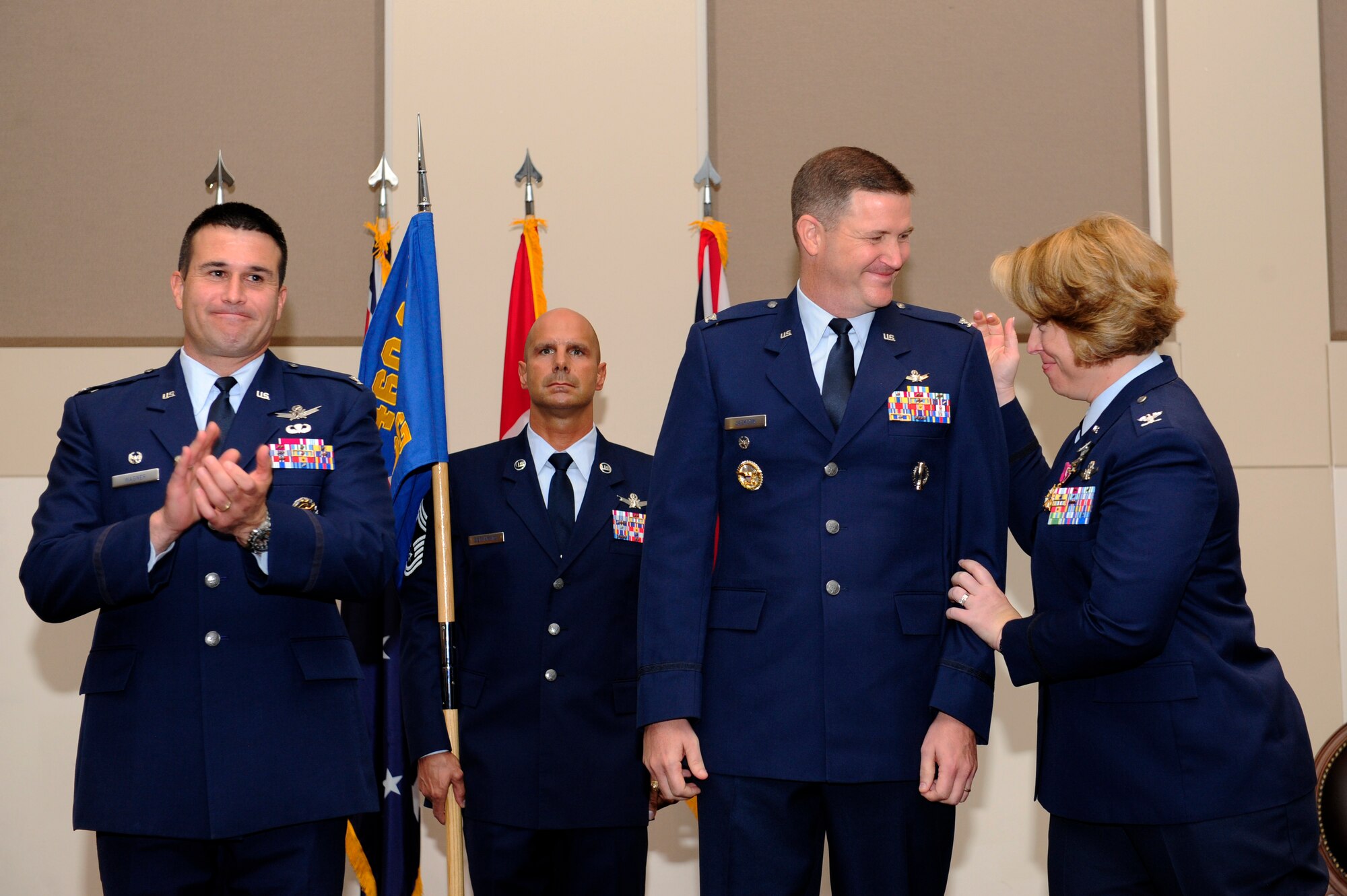 Col. DeAnna Burt, outgoing 460th Operations Group commander, right, congratulates Col. Michael Jackson, 460th OG commander, center, while Col. John Wagner, 460th Space Wing commander, left, applauds during the 460th OG change of command ceremony Aug. 12, 2014, at the Leadership Development Center on Buckley Air Force Base, Colo. Jackson assumed command from Burt, who served as commander of the 460th OG for two years. (U.S. Air Force photo by Airman 1st Class Samantha Saulsbury/Released)