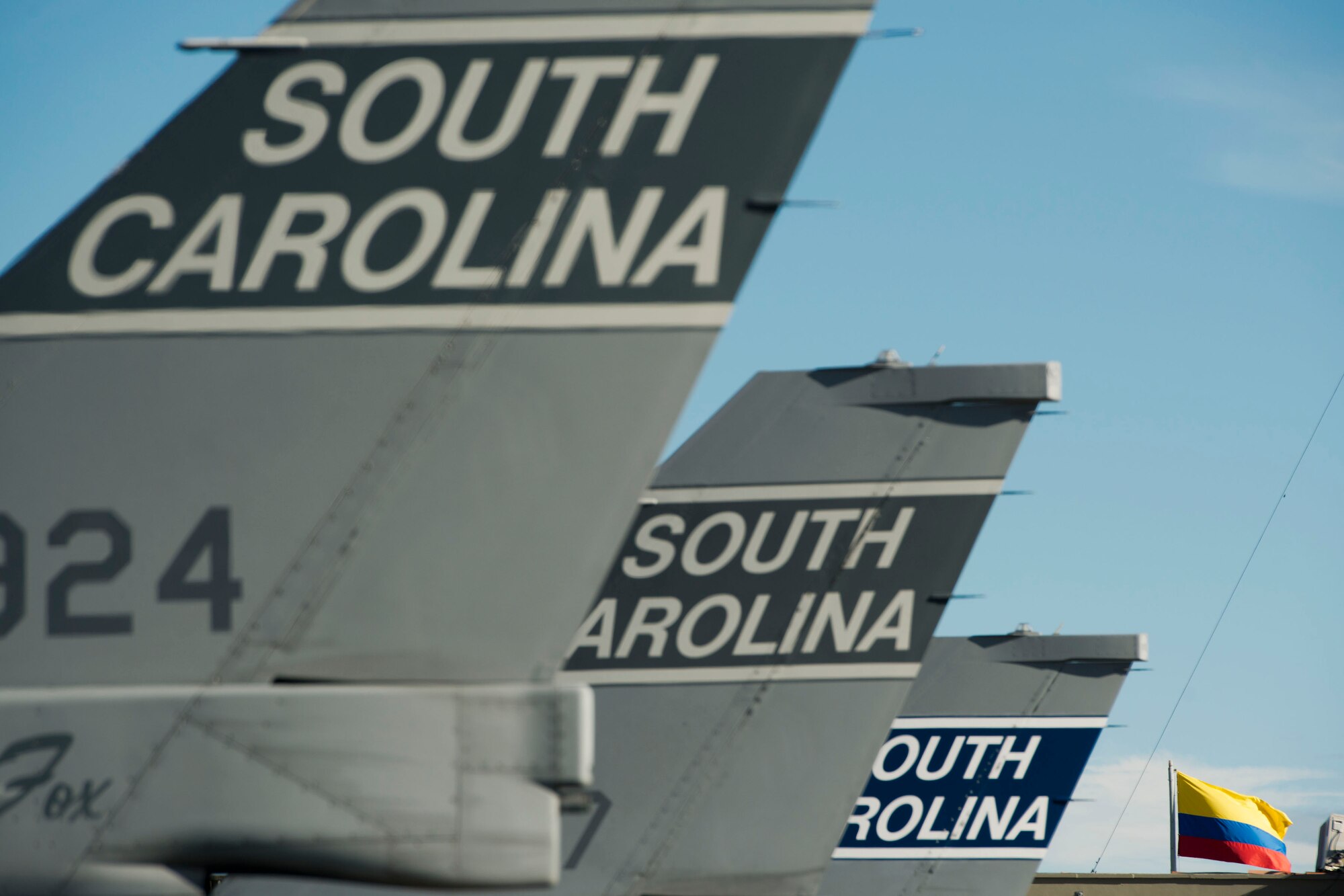 U.S Air Force F-16 Block 52’s fighter tail flashes, assigned to the 169th Fighter Wing from McEntire Joint National Guard Base of the South Carolina Air National Guard, are lined-up iin front of a Republic of Colombia flag at Rionegro, Colombia, during Relampago (Lightning) 2014, Aug. 9, 2014. Relampago is a combined air cooperation engagement with the Republic of Colombia. One hundred Airmen and six F-16s are participating in the first major joint-air training opportunity under the auspices of the South Carolina National Guard's State Partnership Program with the country of Colombia. (U.S. Air National Guard photo by Tech. Sgt. Jorge Intriago/Released)