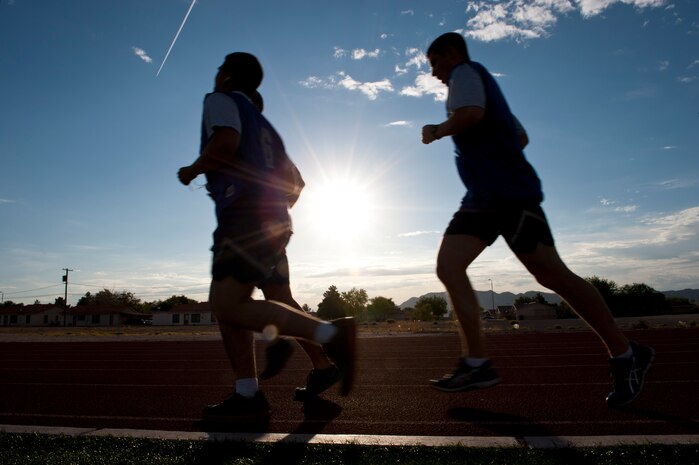 Airman complete their final lap of the 1.5-mile run portion of the Air Force fitness assessment at the Warrior Fitness Center, Nellis Air Force Base, Nev., Aug. 12, 2014. Runners are allowed to have a fellow Airman keep pace with them during the run for motivation and encouragement. (U.S. Air Force photo by Airman 1st Class Thomas Spangler)